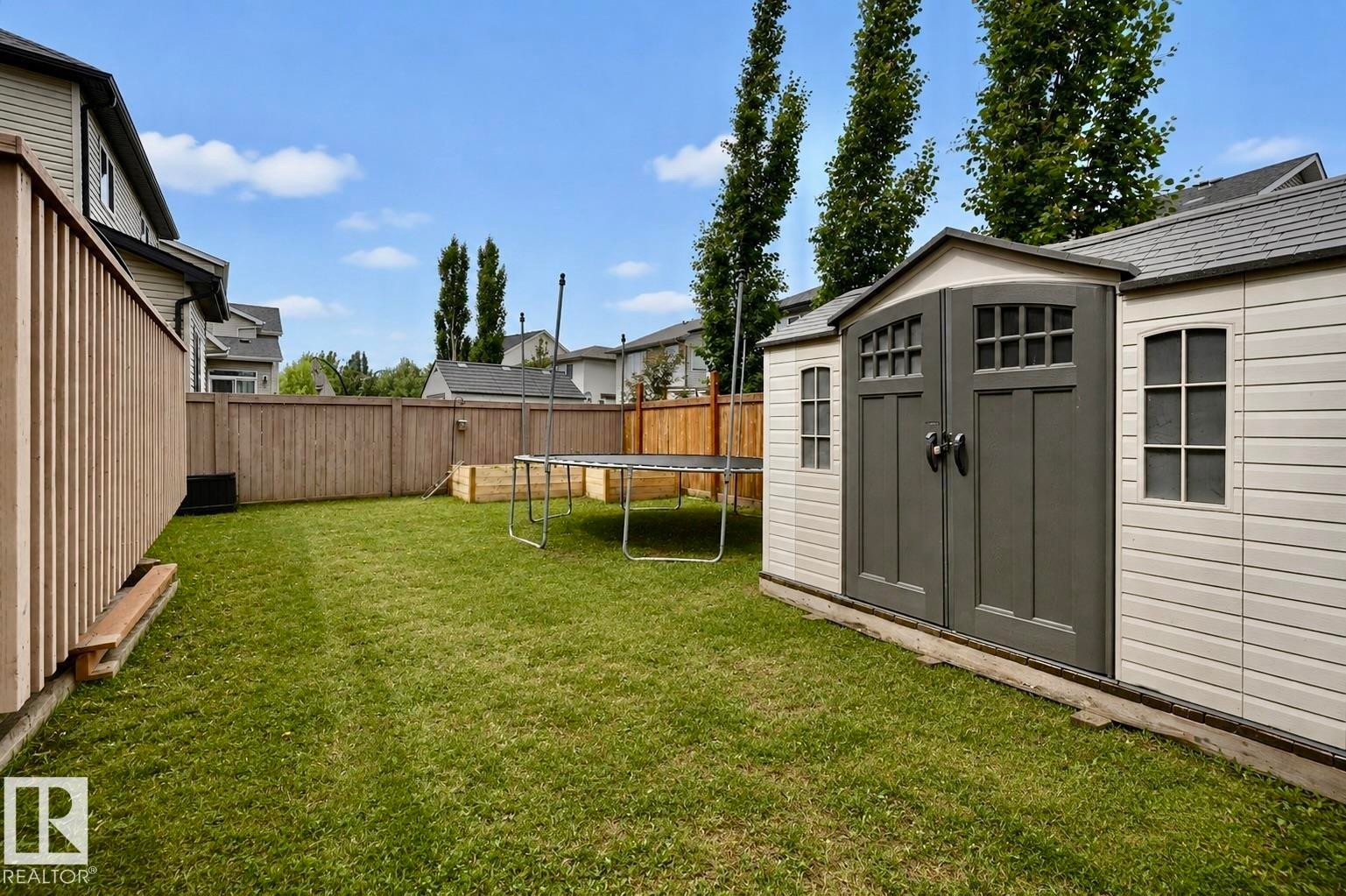 Spacious rear yard featuring a lawn area, wood privacy fencing, and a permanent storage shed with double doors - 21928 97 Avenue Nw, Edmonton, AB - Outdoor