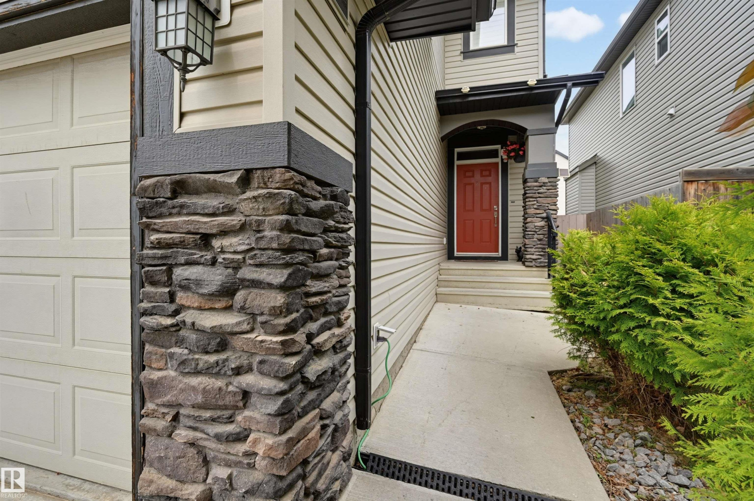 Exterior featuring a stone column, siding, and a paneled garage door - 21928 97 Avenue Nw, Edmonton, AB - Outdoor With Exterior