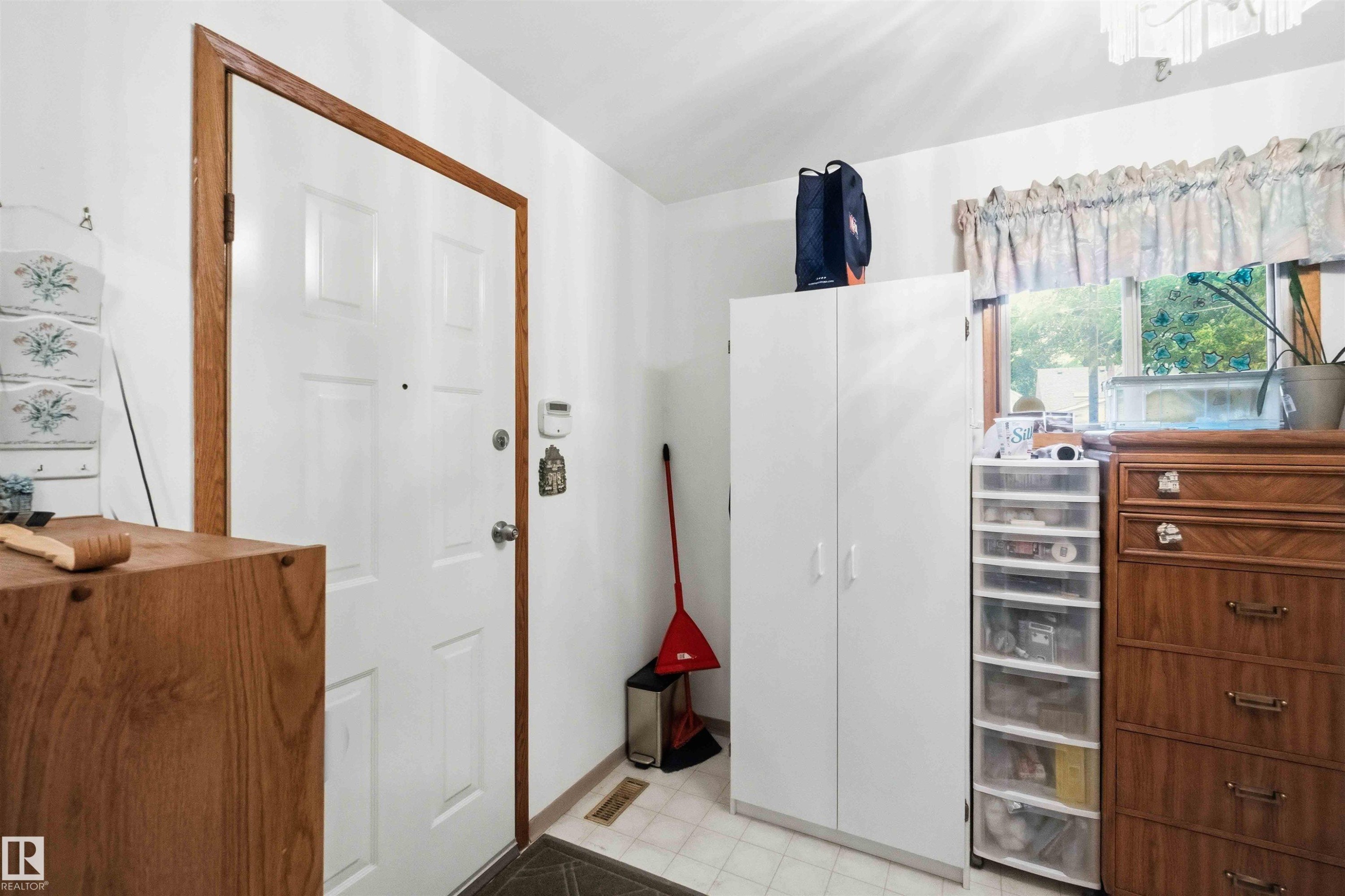 White paneled entry door with wood-finish trim, complemented by white walls and a window with wood-finish casing - 12016 61 Street, Edmonton, AB