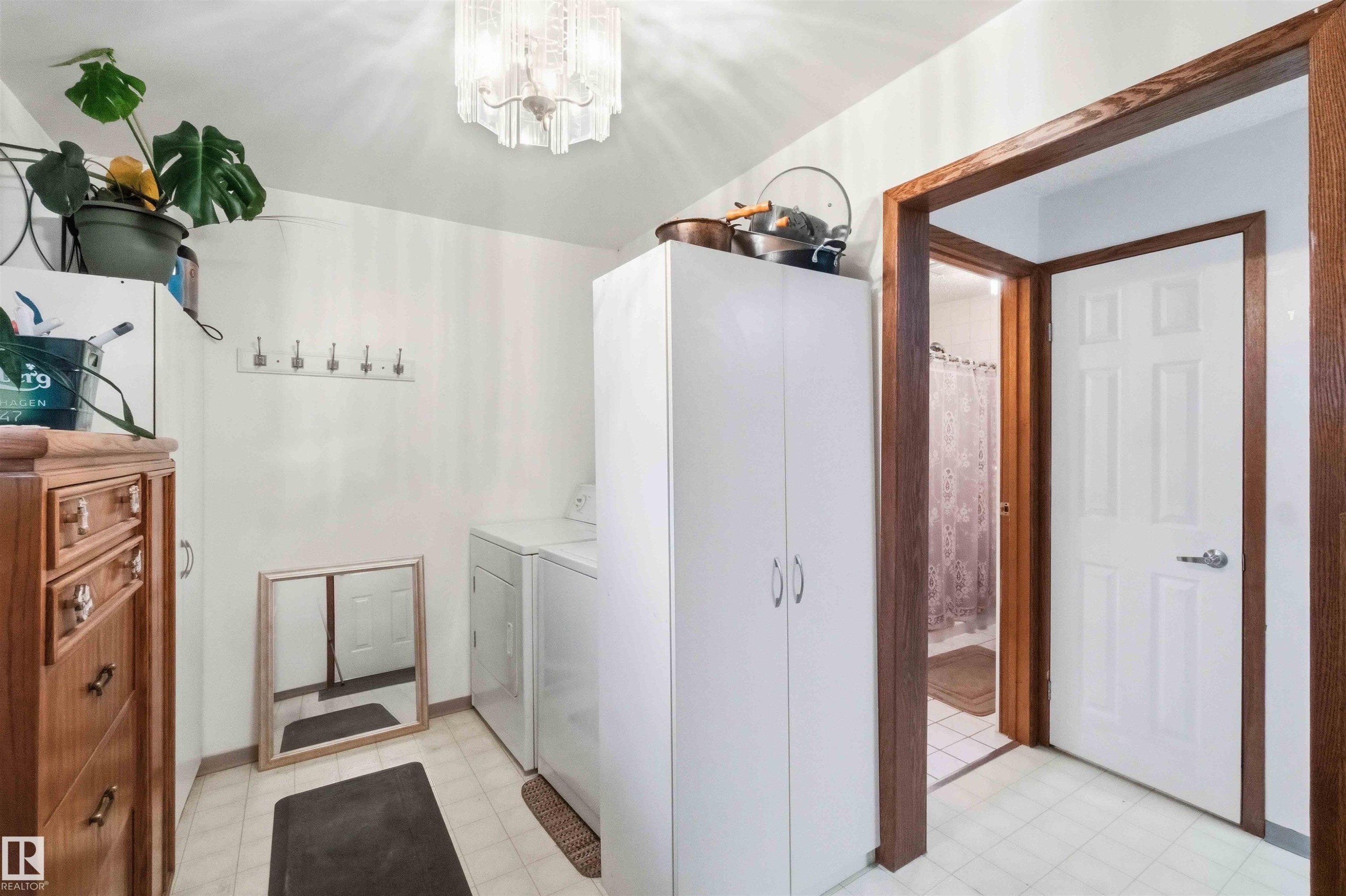 Utility space featuring tile flooring, white walls, and a multi-paneled door with wood trim - 12016 61 Street, Edmonton, AB