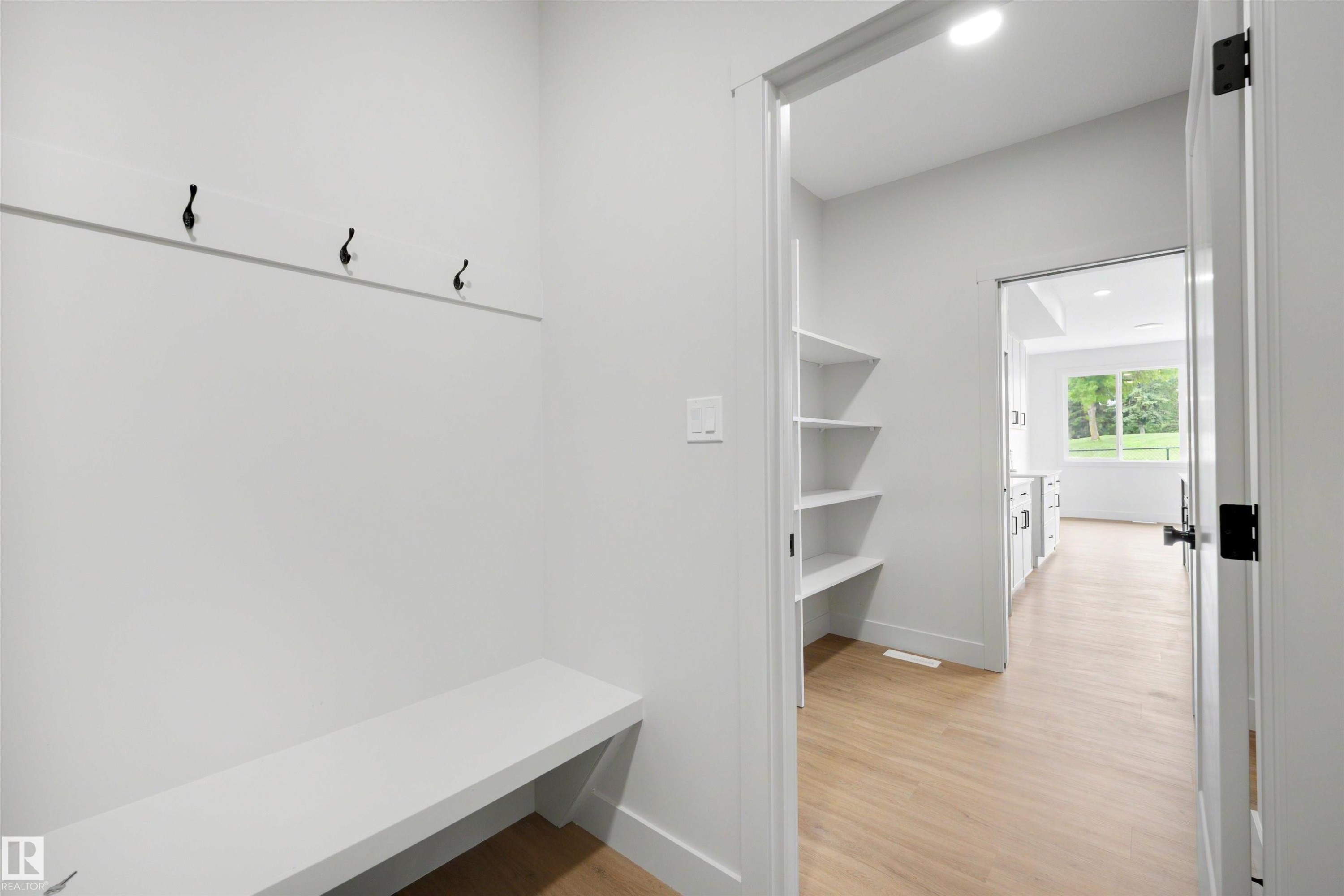 Mudroom entry with built-in bench, black coat hooks, and recessed lighting - 24 Grayson Green, Stony Plain, AB