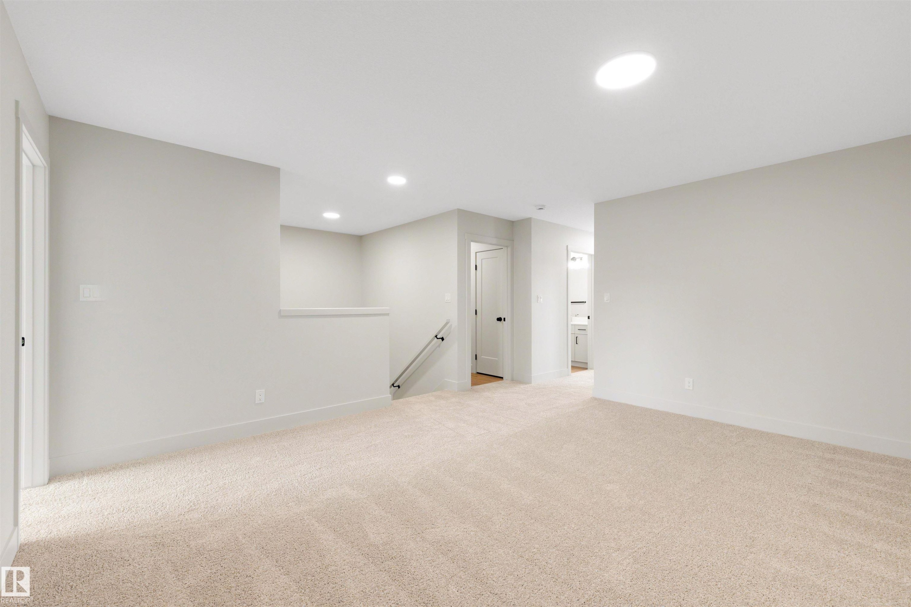 Spacious carpeted room featuring recessed lighting, a skylight, light grey walls, white trim, and doors with matte black hardware - 24 Grayson Green, Stony Plain, AB