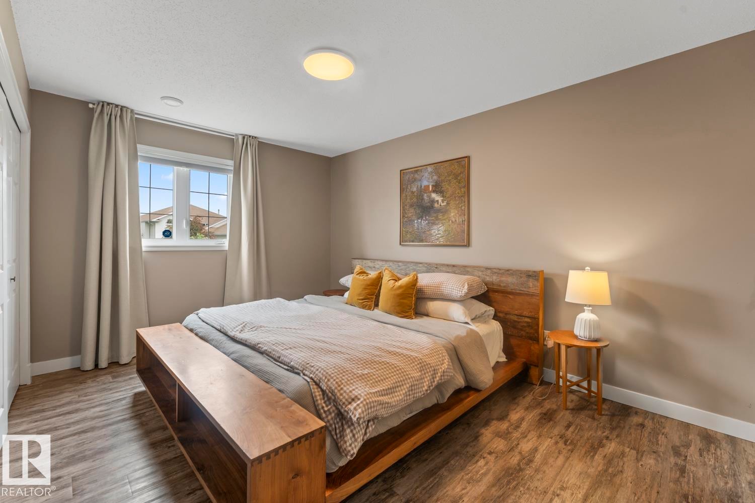 Bedroom featuring wood-finish flooring, a window with white trim, and neutral wall paint - 2602 Delta Road, Cold Lake, AB