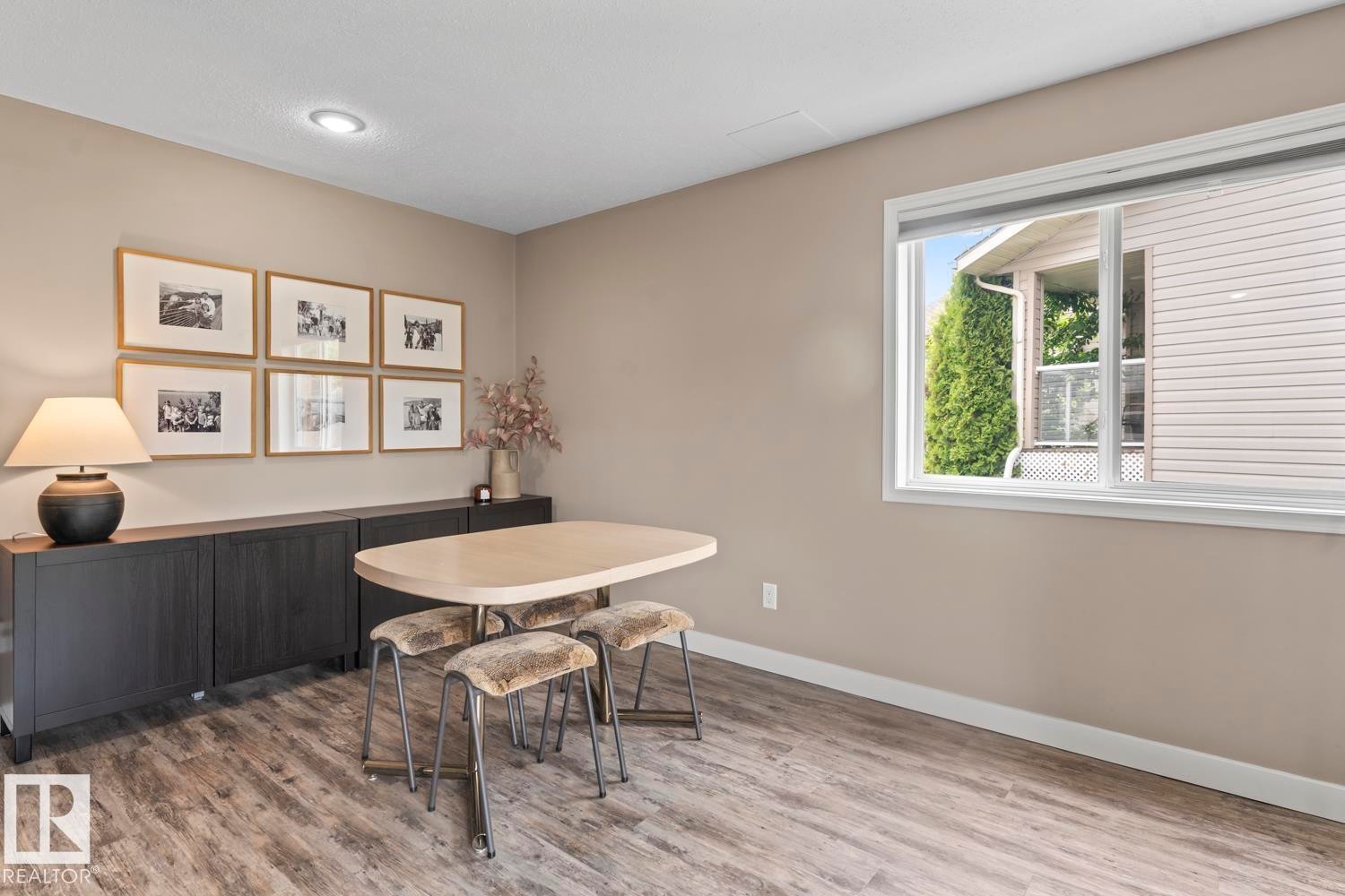 Spacious room with wood-finish flooring, recessed ceiling lighting, and a large white-framed window - 2602 Delta Road, Cold Lake, AB