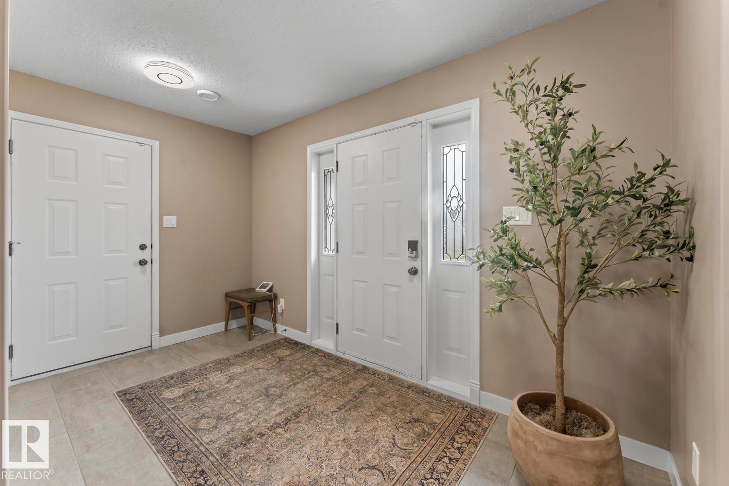 Entryway featuring a panel door with decorative glass sidelights, a second white panel door, and neutral-toned wall paint - 2602 Delta Road, Cold Lake, AB