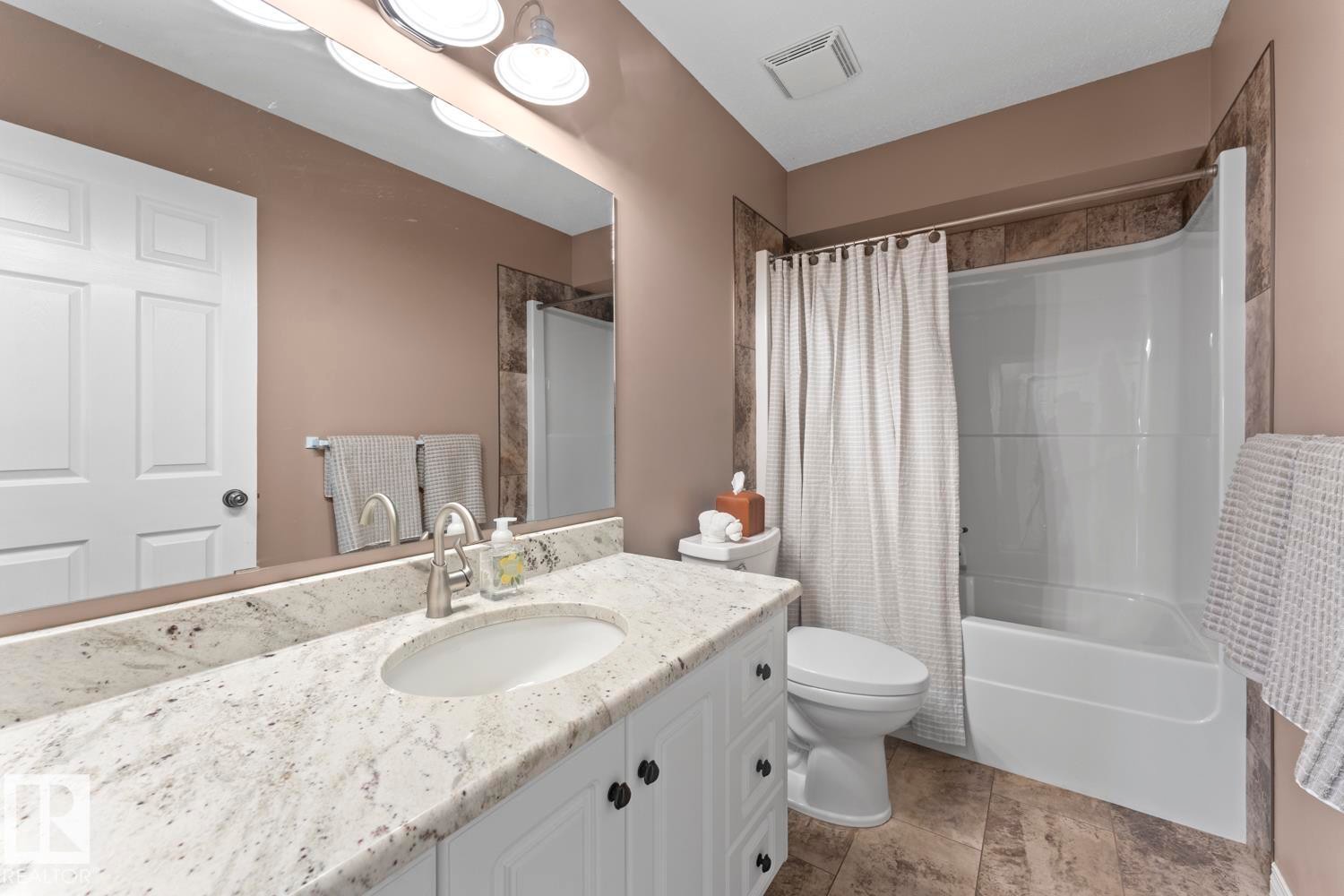 Bathroom vanity with a speckled countertop, undermount sink, and brushed nickel faucet - 2602 Delta Road, Cold Lake, AB
