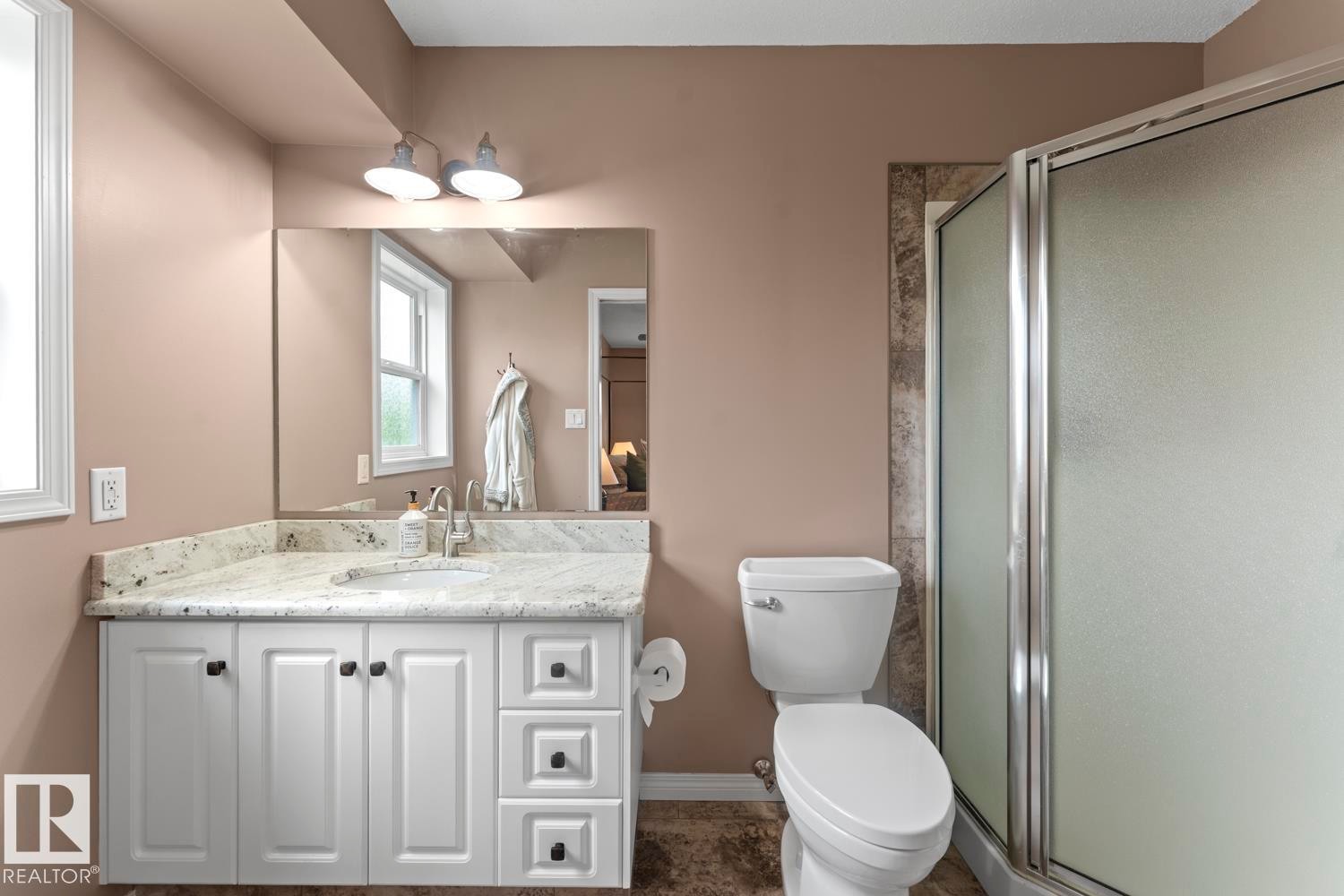 Bathroom featuring a white vanity with panel doors, a light-toned countertop, and a rectangular mirror - 2602 Delta Road, Cold Lake, AB