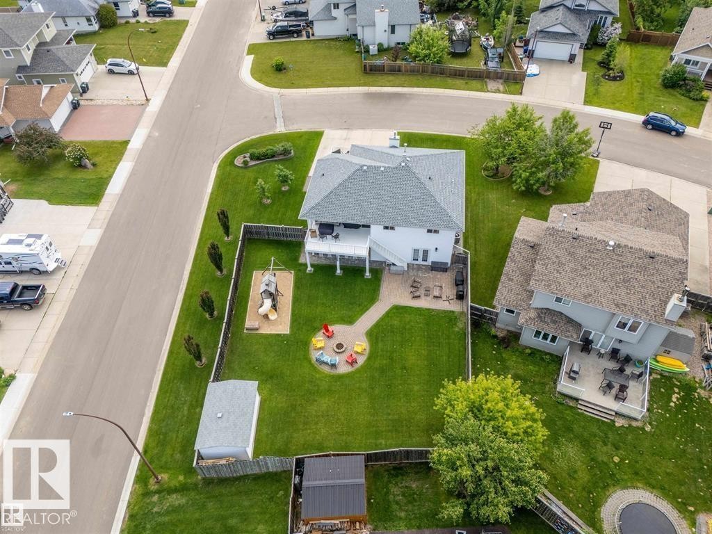 Rear exterior featuring a large green lawn, a ground-level patio, an elevated deck, and a detached shed - 2602 Delta Road, Cold Lake, AB