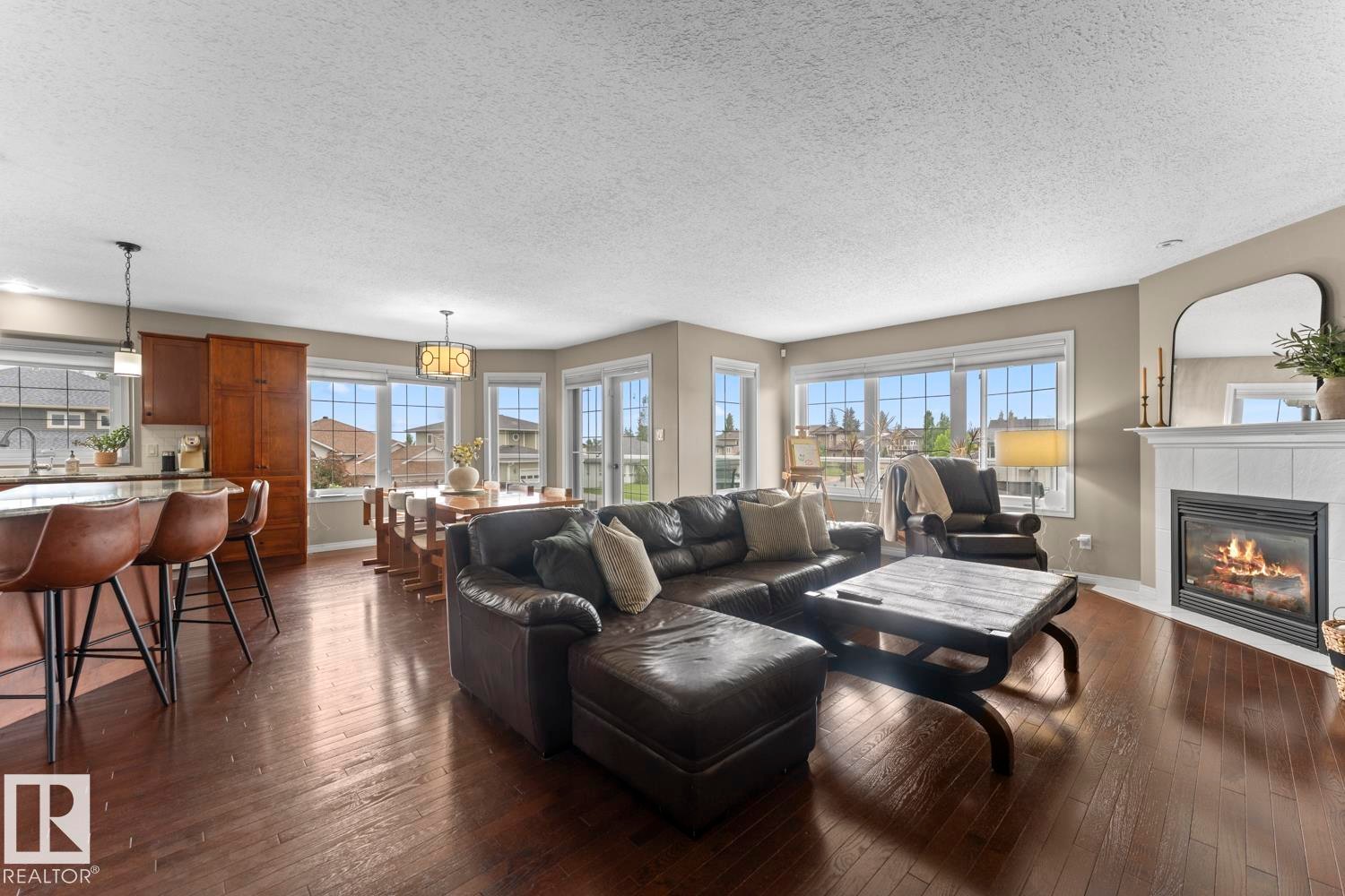 Spacious living area featuring dark wood-finish flooring, a white mantel fireplace, and a large bay window - 2602 Delta Road, Cold Lake, AB