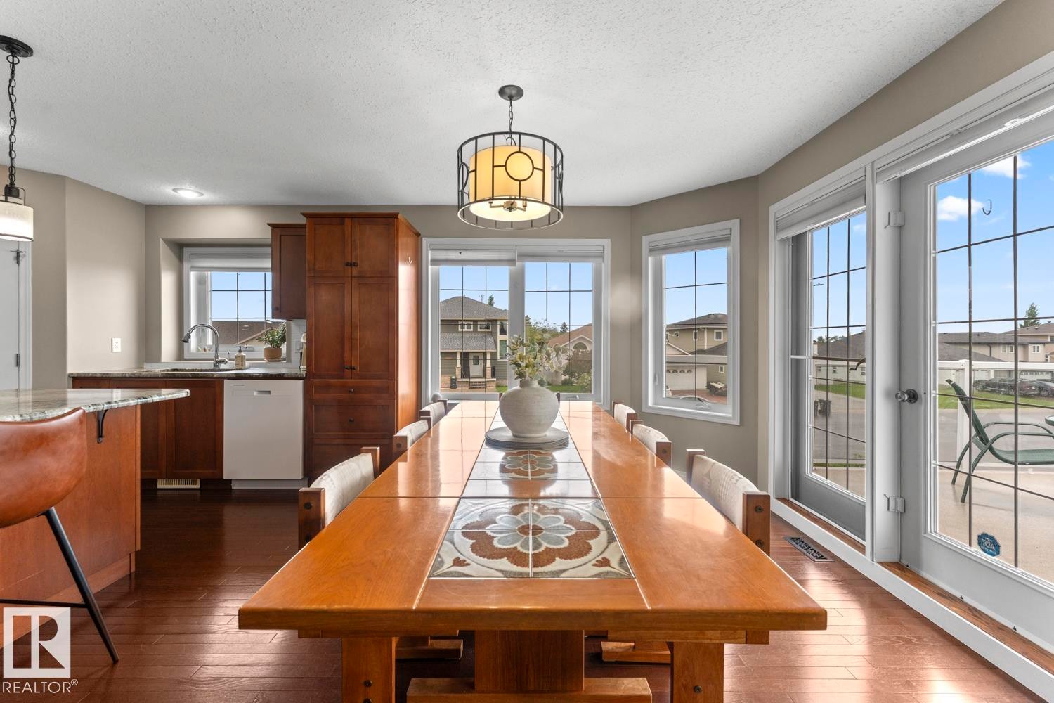 Open-concept living space featuring wood-finish flooring, a kitchen with rich wood cabinetry, a granite-look island, and a built-in dishwasher - 2602 Delta Road, Cold Lake, AB