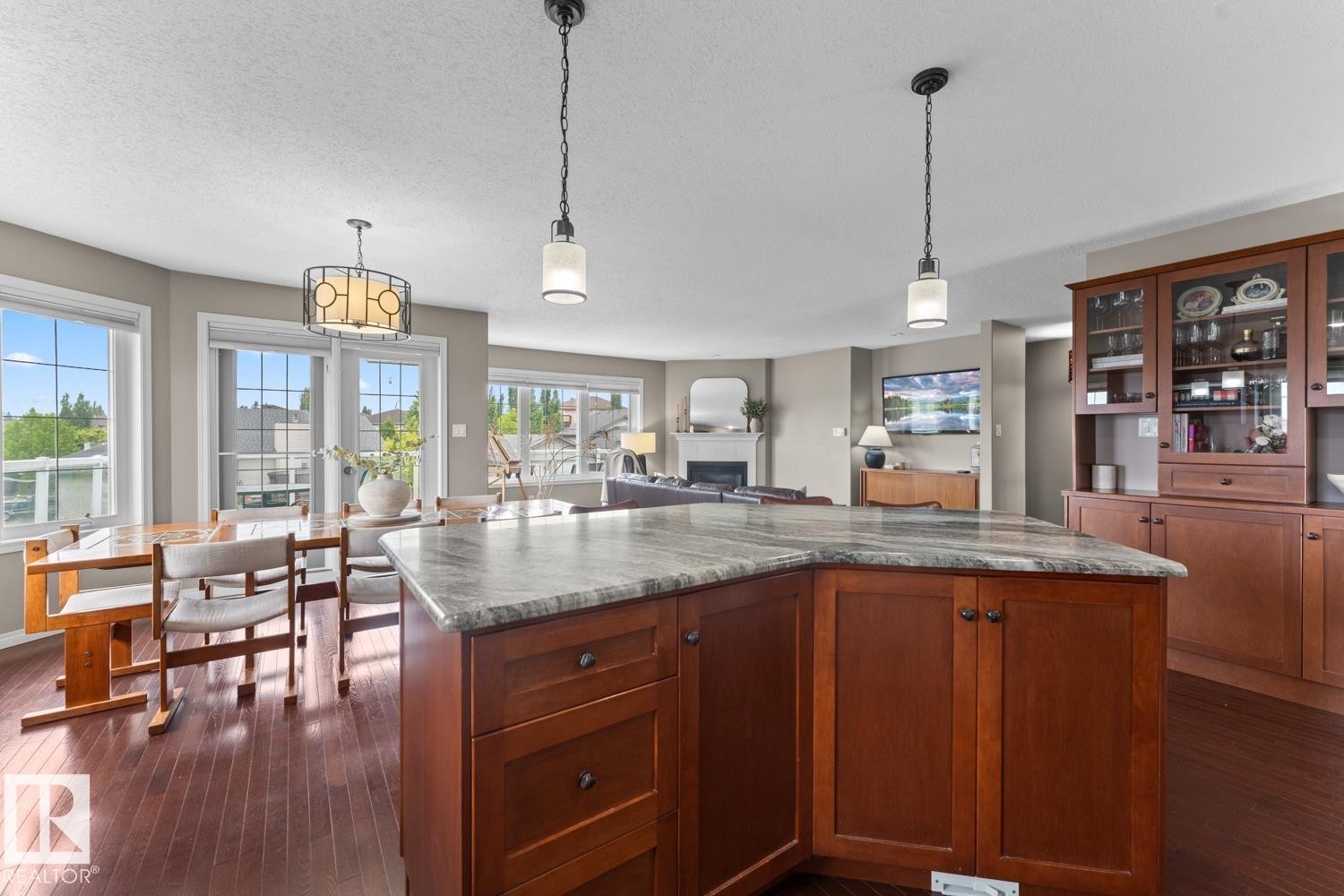 Kitchen island with a light-toned countertop, pendant lighting, and rich wood-finish cabinetry - 2602 Delta Road, Cold Lake, AB