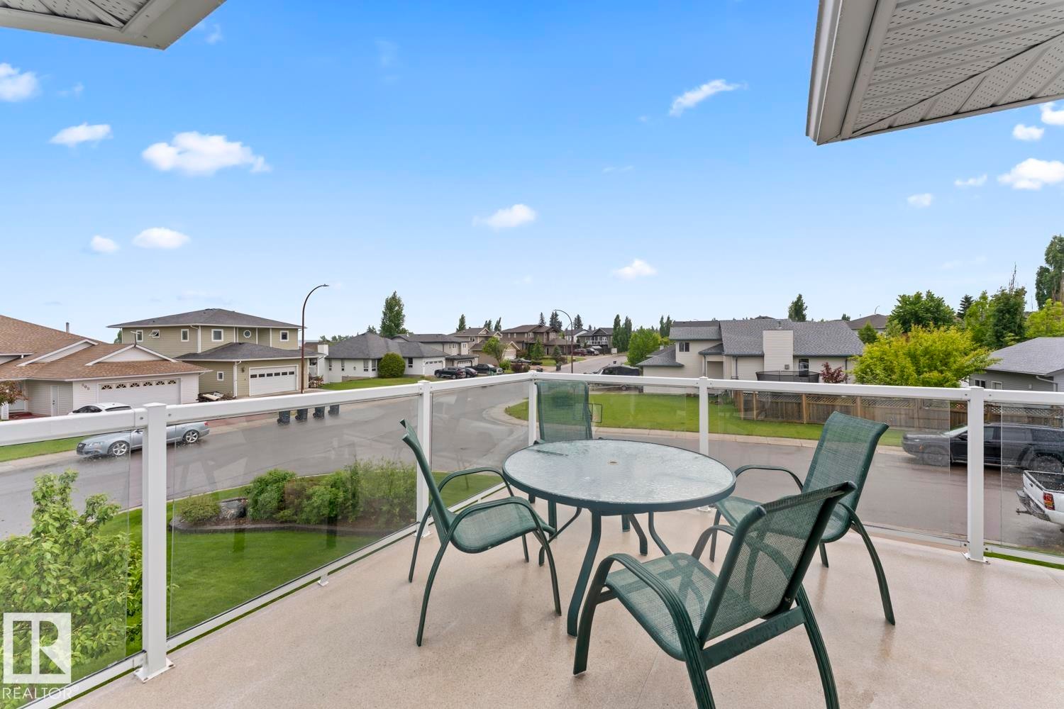 Outdoor balcony with a glass railing system and a textured concrete surface - 2602 Delta Road, Cold Lake, AB