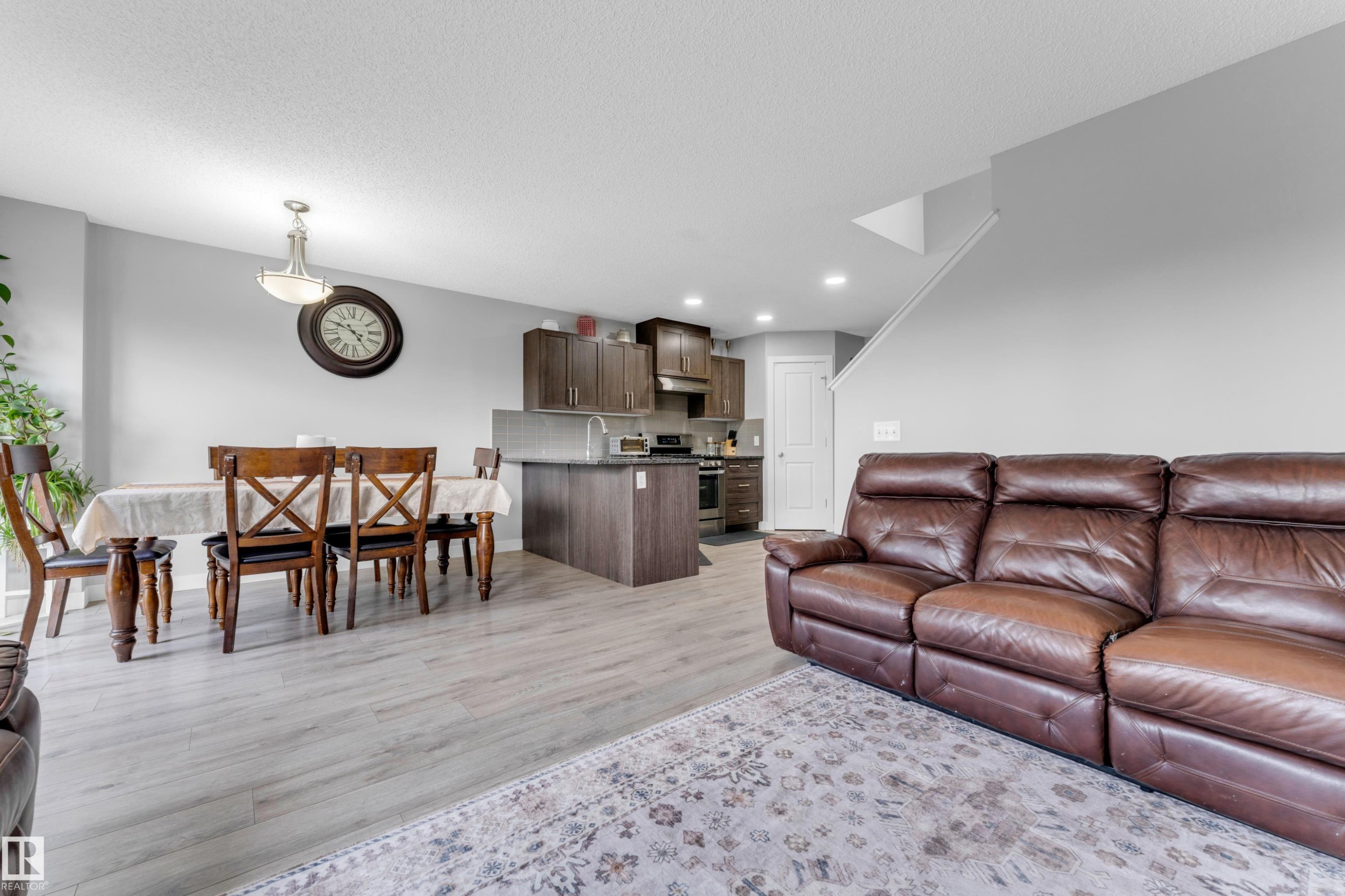 Open-concept living space featuring wood-finish flooring, recessed lighting, and a neutral color palette - 1750 27 Street, Edmonton, AB