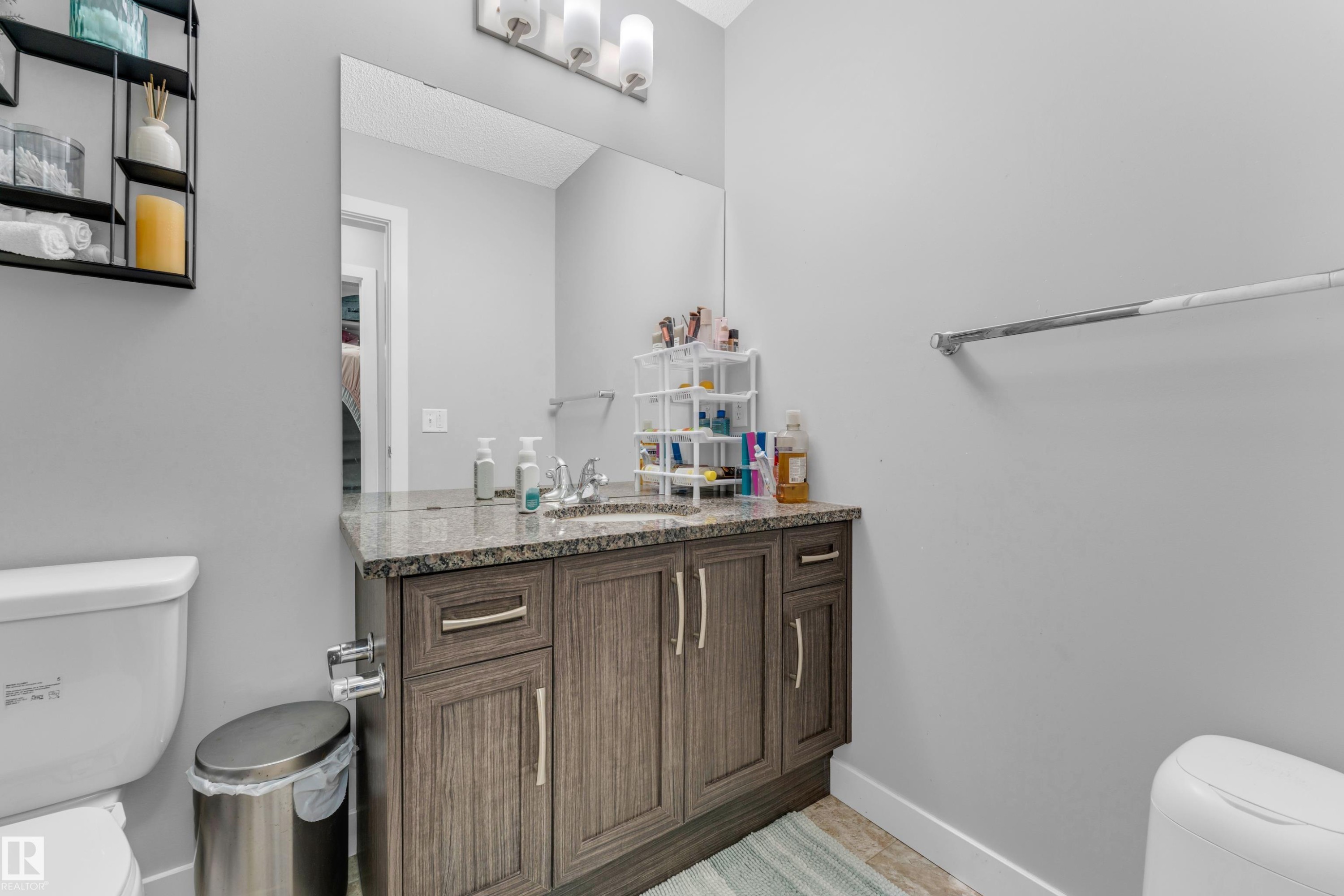 Bathroom vanity featuring a granite countertop, integrated sink, and wood-finish cabinetry with brushed nickel hardware - 1750 27 Street, Edmonton, AB
