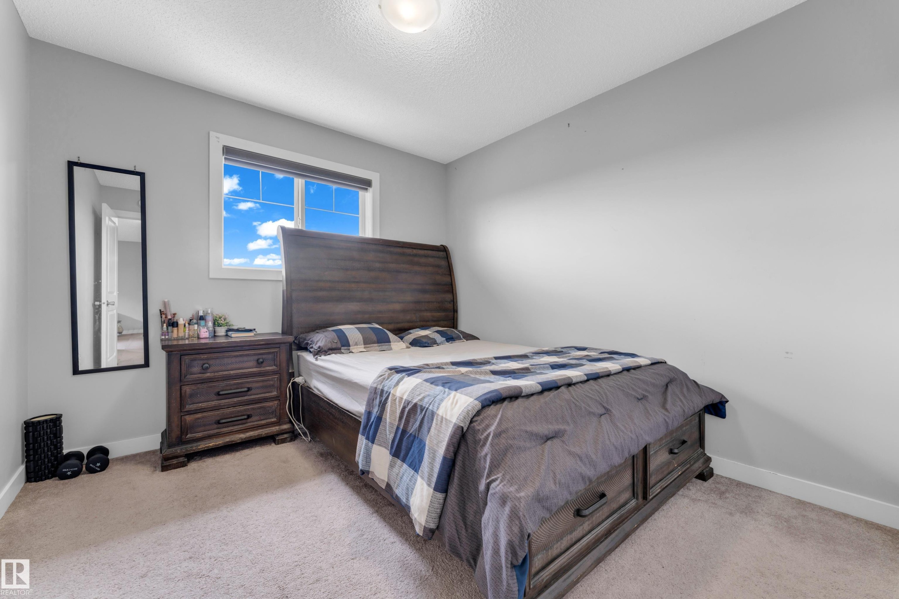 Carpeted room featuring a window with natural light, neutral wall colors, a ceiling-mounted light fixture, and white baseboards - 1750 27 Street, Edmonton, AB