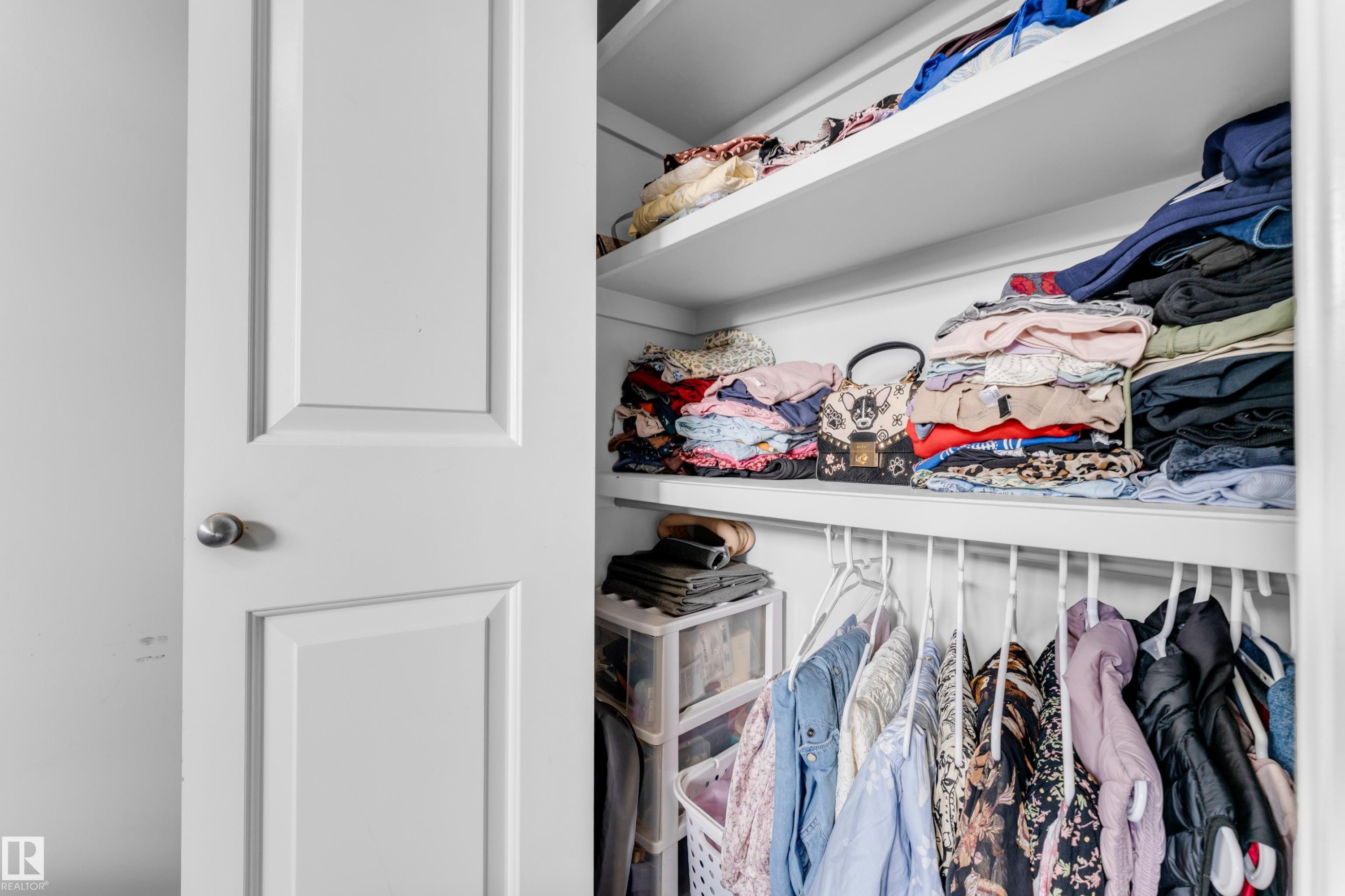 White interior door with a brushed nickel knob opening to a closet featuring white shelving and a hanging rod - 1750 27 Street, Edmonton, AB