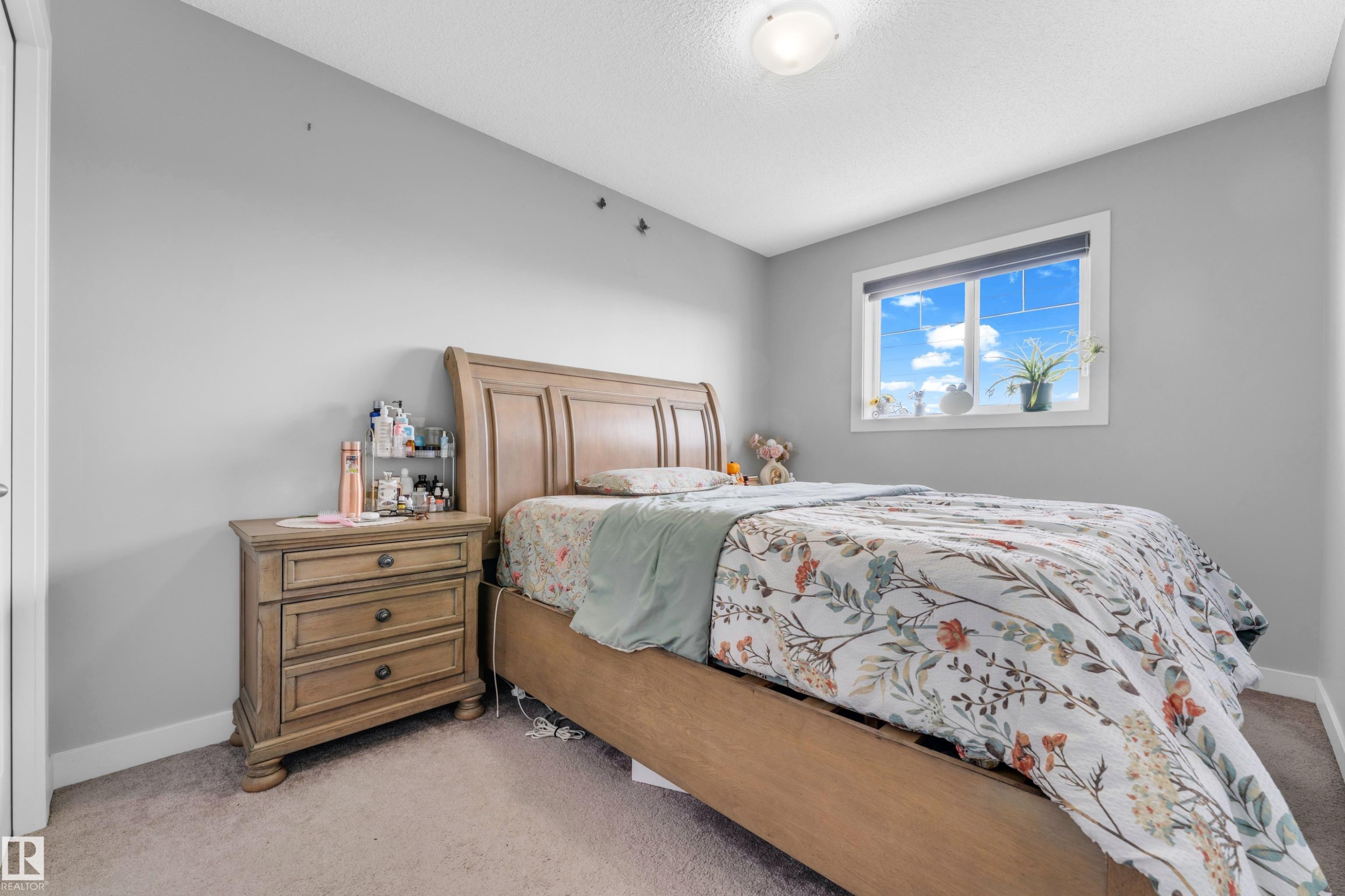 Bedroom featuring a neutral color palette, ceiling-mounted light fixture, white trim, and a window with a roller shade - 1750 27 Street, Edmonton, AB