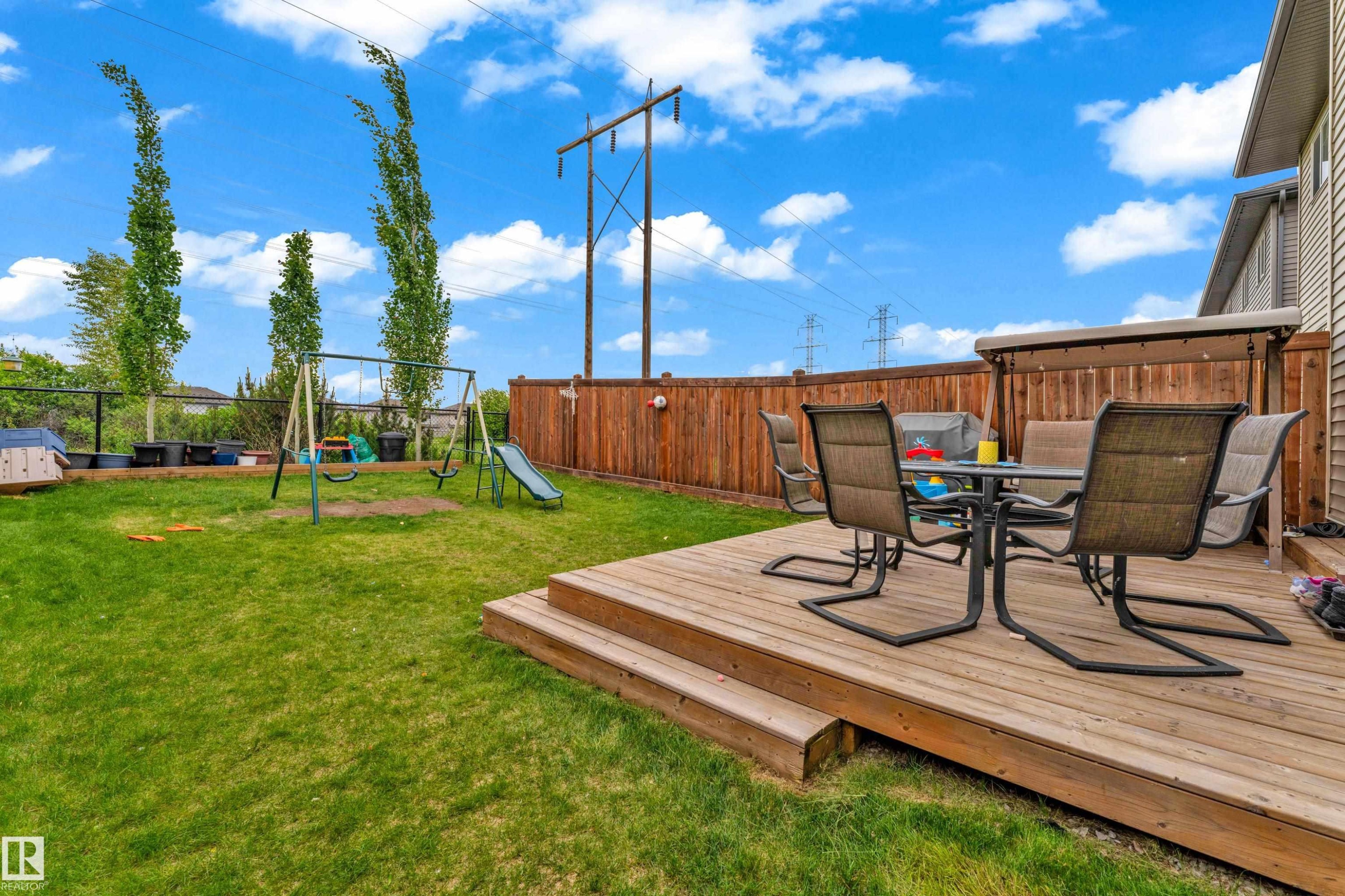 Expansive backyard featuring a multi-level wood deck, manicured lawn, and privacy fencing - 1750 27 Street, Edmonton, AB