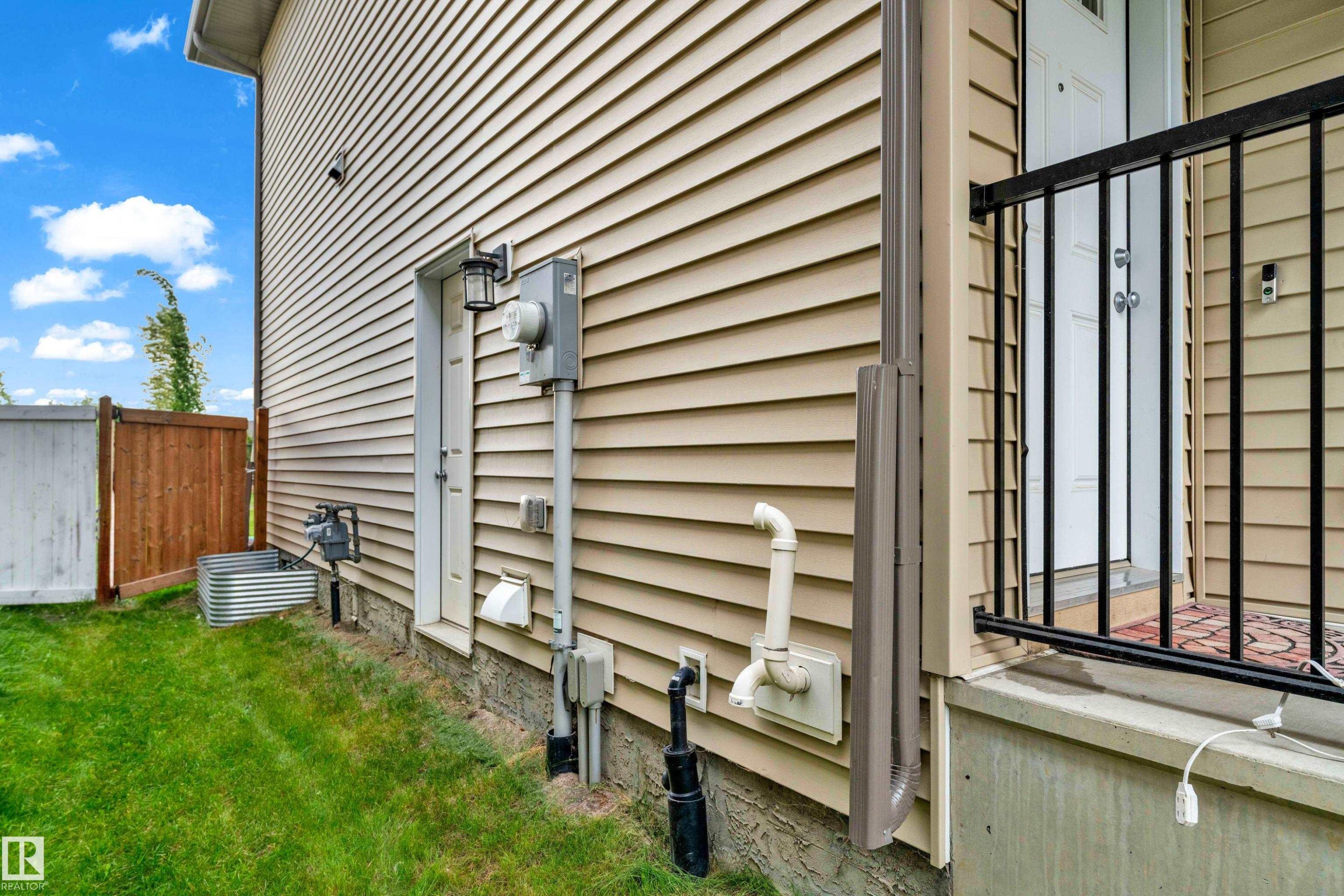 Side exterior featuring tan horizontal siding and a white entry door - 1750 27 Street, Edmonton, AB