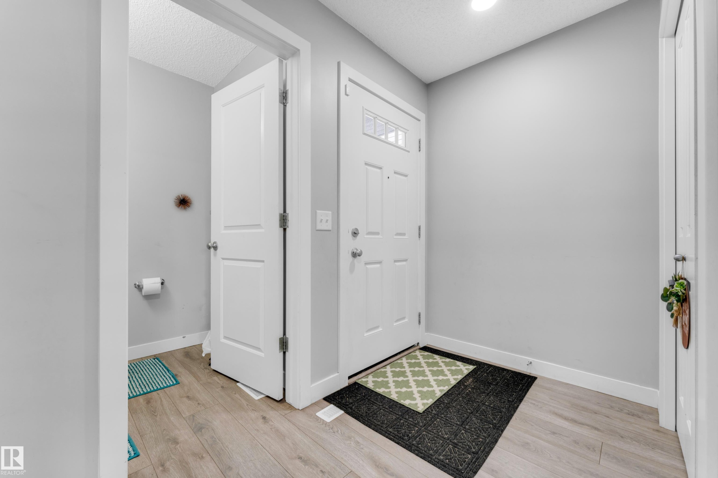 Entryway featuring wood-finish flooring, a paneled front door with decorative glass inserts, and a recessed ceiling light - 1750 27 Street, Edmonton, AB