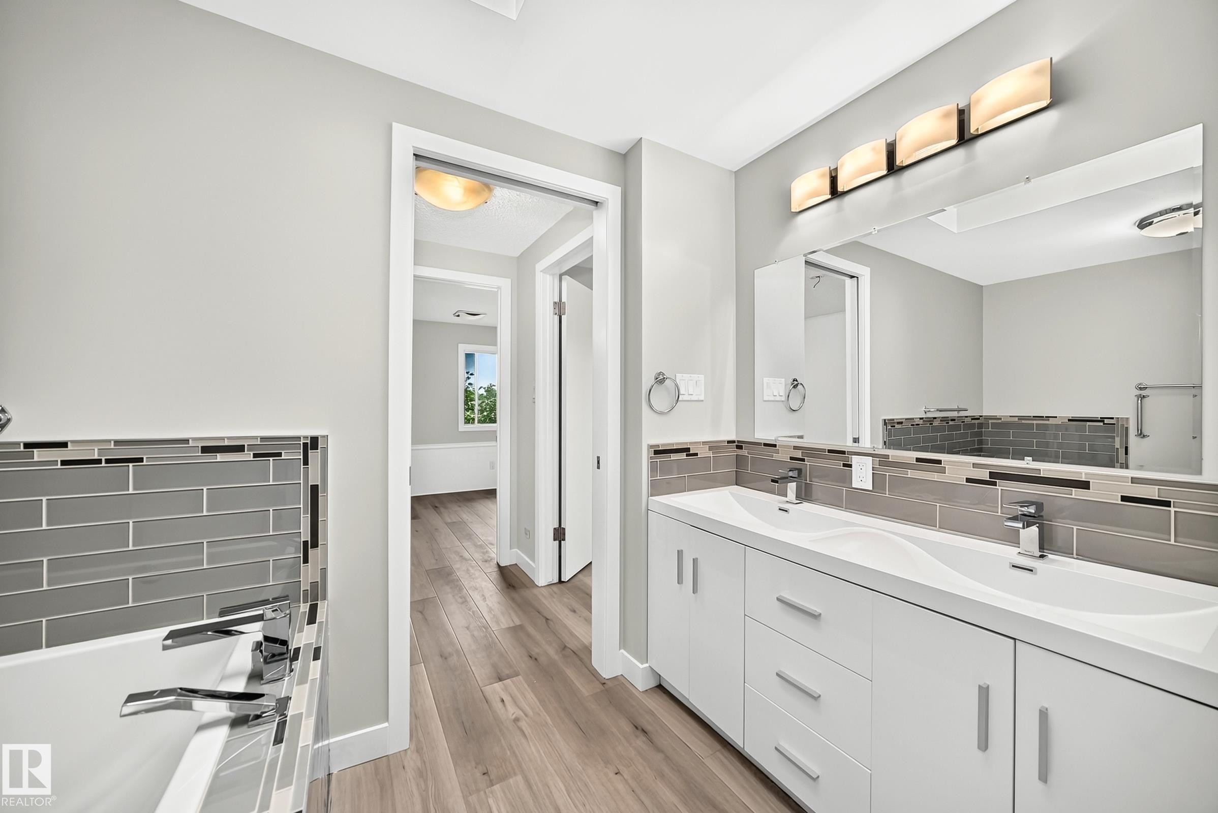 Dual vanity with integrated sinks, chrome fixtures, and a multi-tone subway tile backsplash - 18636 71 Avenue, Edmonton, AB