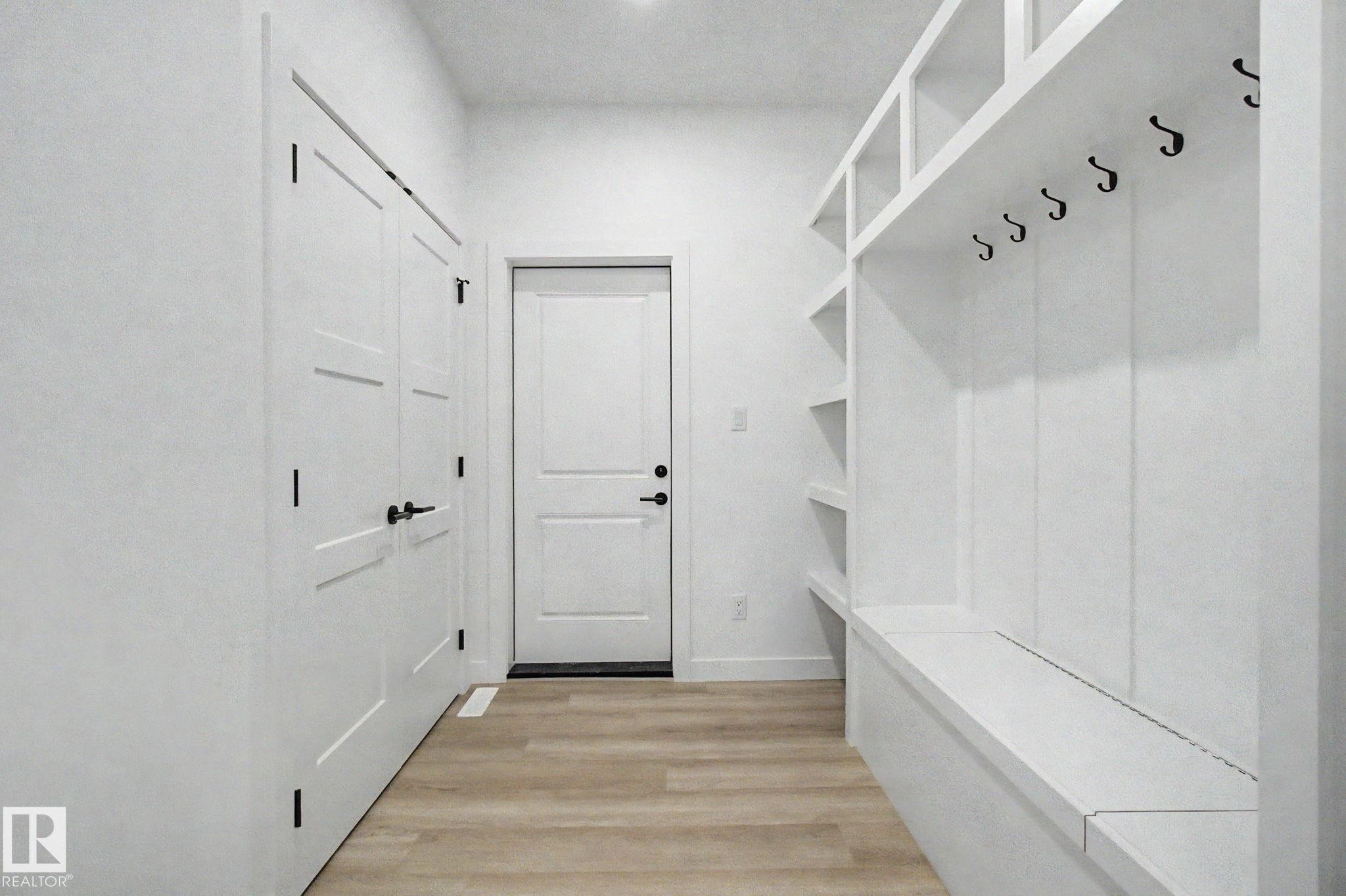 Entryway featuring wood-finish flooring, built-in mudroom storage with integrated bench seating, and multiple storage cubbies - 4 Willow Heights Drive, Stony Plain, AB