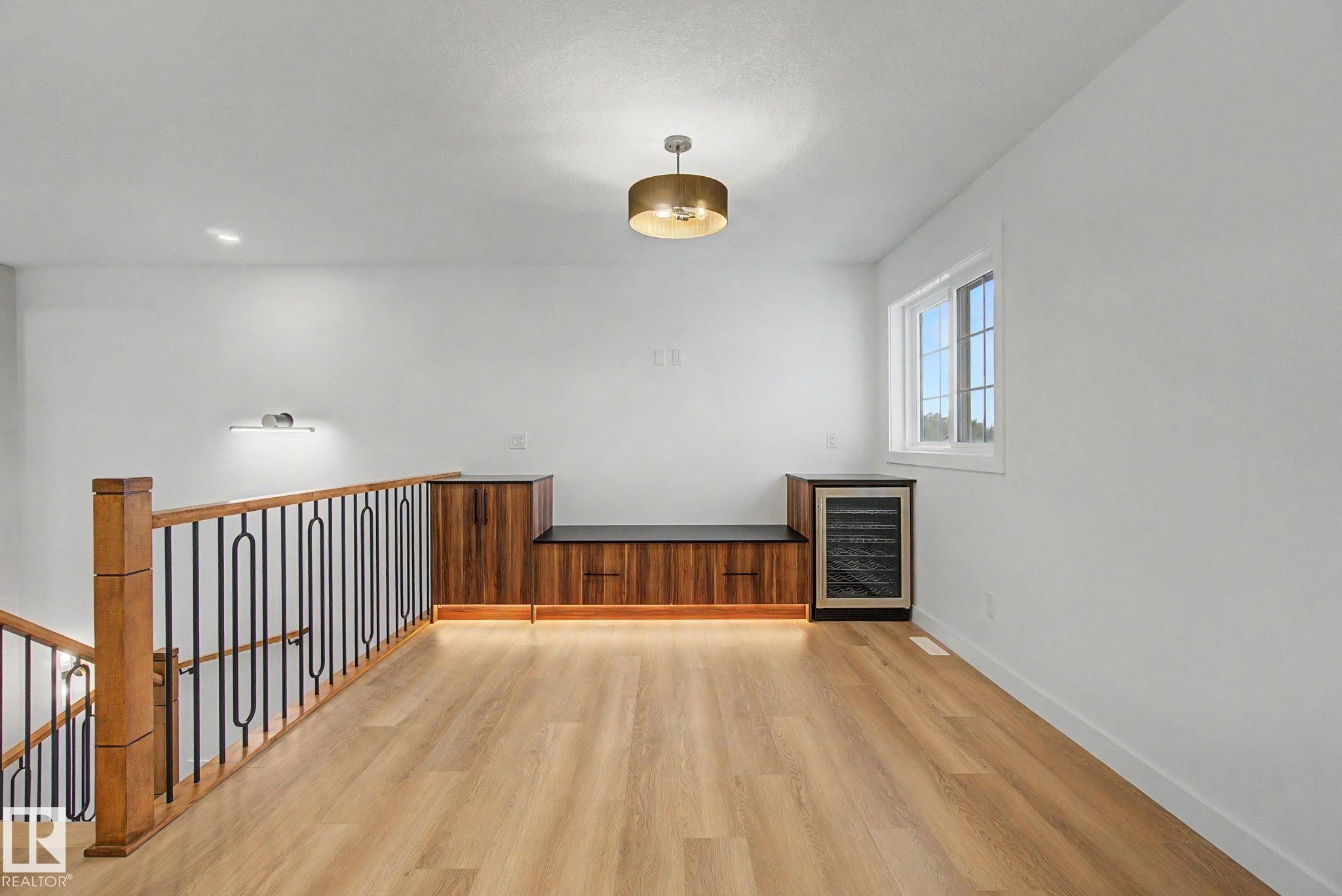 Wood-finish flooring throughout, featuring a staircase with wood newel posts and iron balusters - 4 Willow Heights Drive, Stony Plain, AB