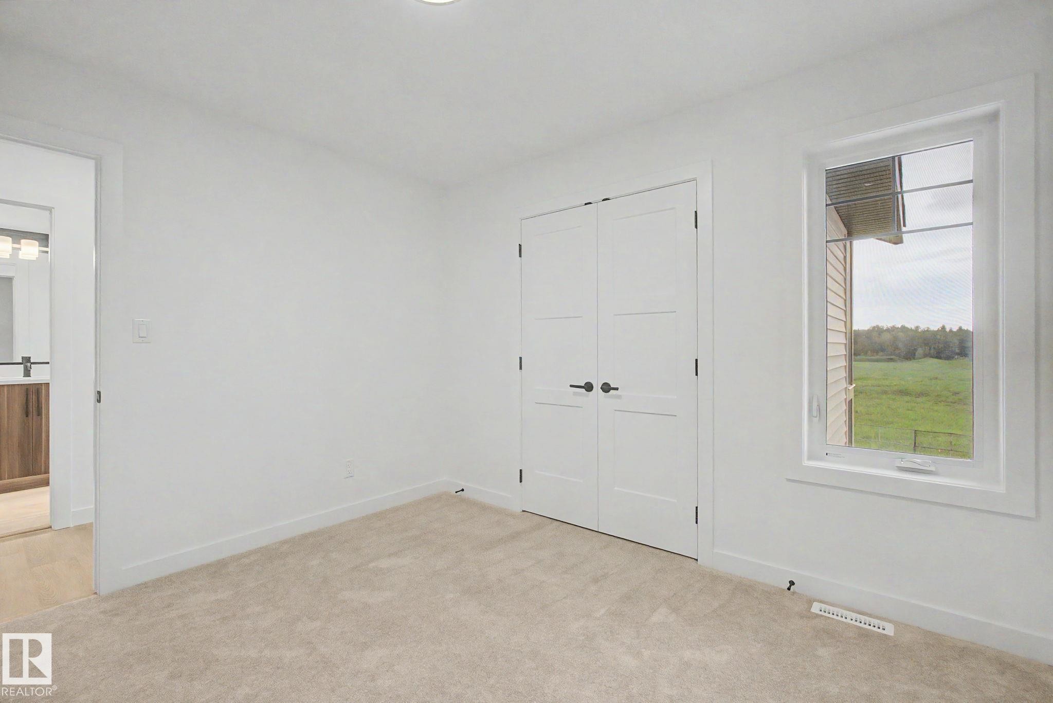 Bedroom featuring neutral carpeting, white walls, and a window with white trim - 4 Willow Heights Drive, Stony Plain, AB