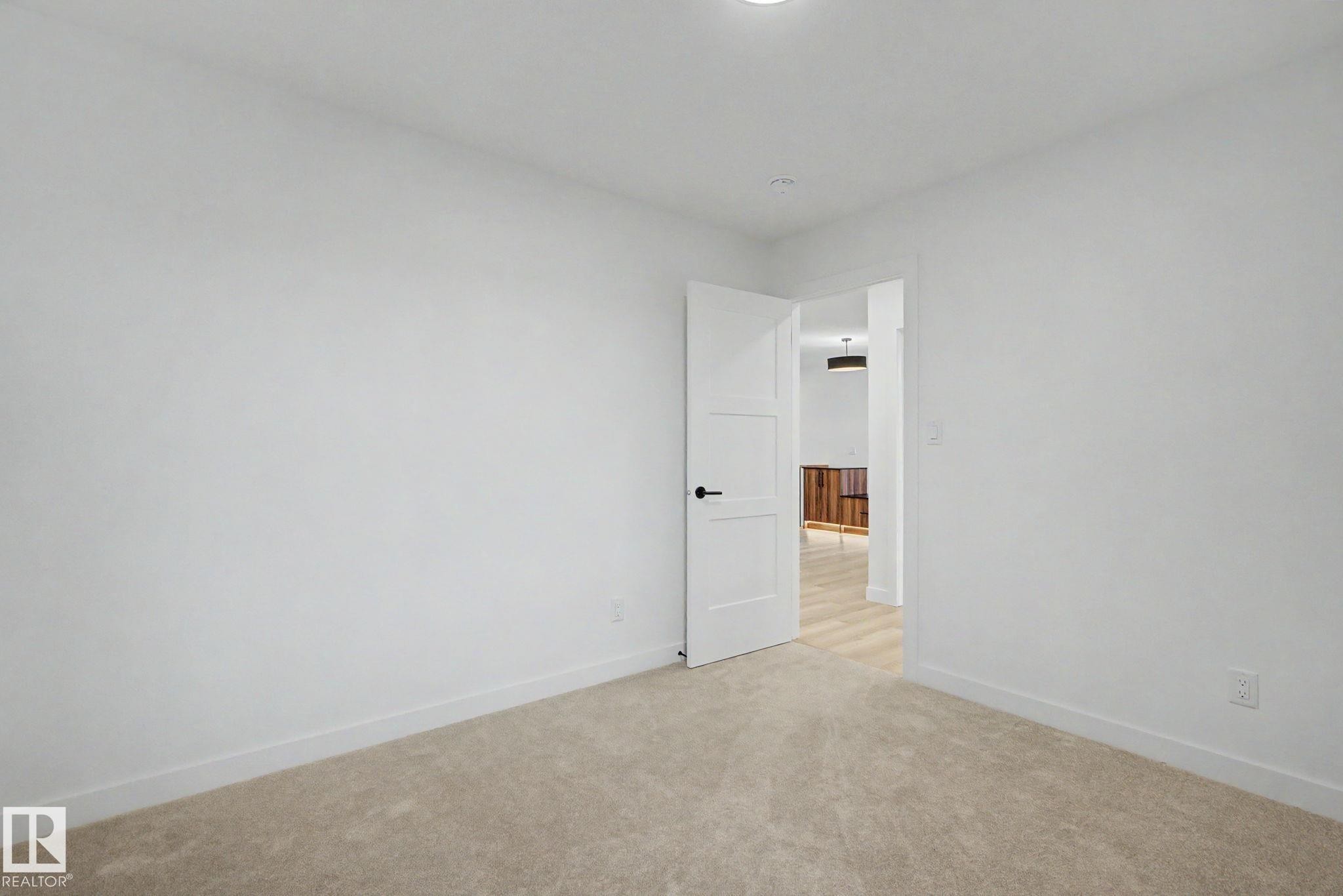 Room featuring neutral-toned carpeting, white walls, and a modern three-panel interior door with matte black hardware - 4 Willow Heights Drive, Stony Plain, AB