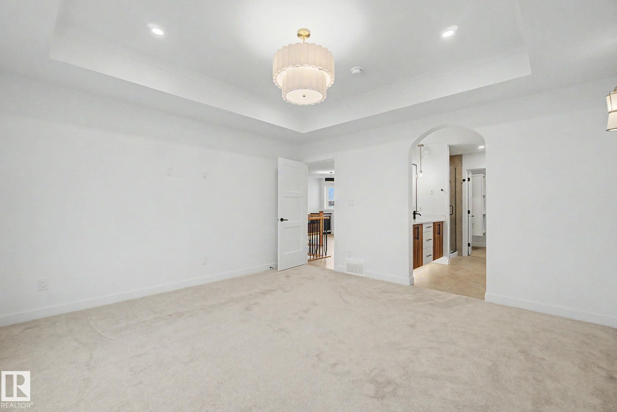 Spacious room featuring light-colored carpeting and a tray ceiling with recessed lighting - 4 Willow Heights Drive, Stony Plain, AB