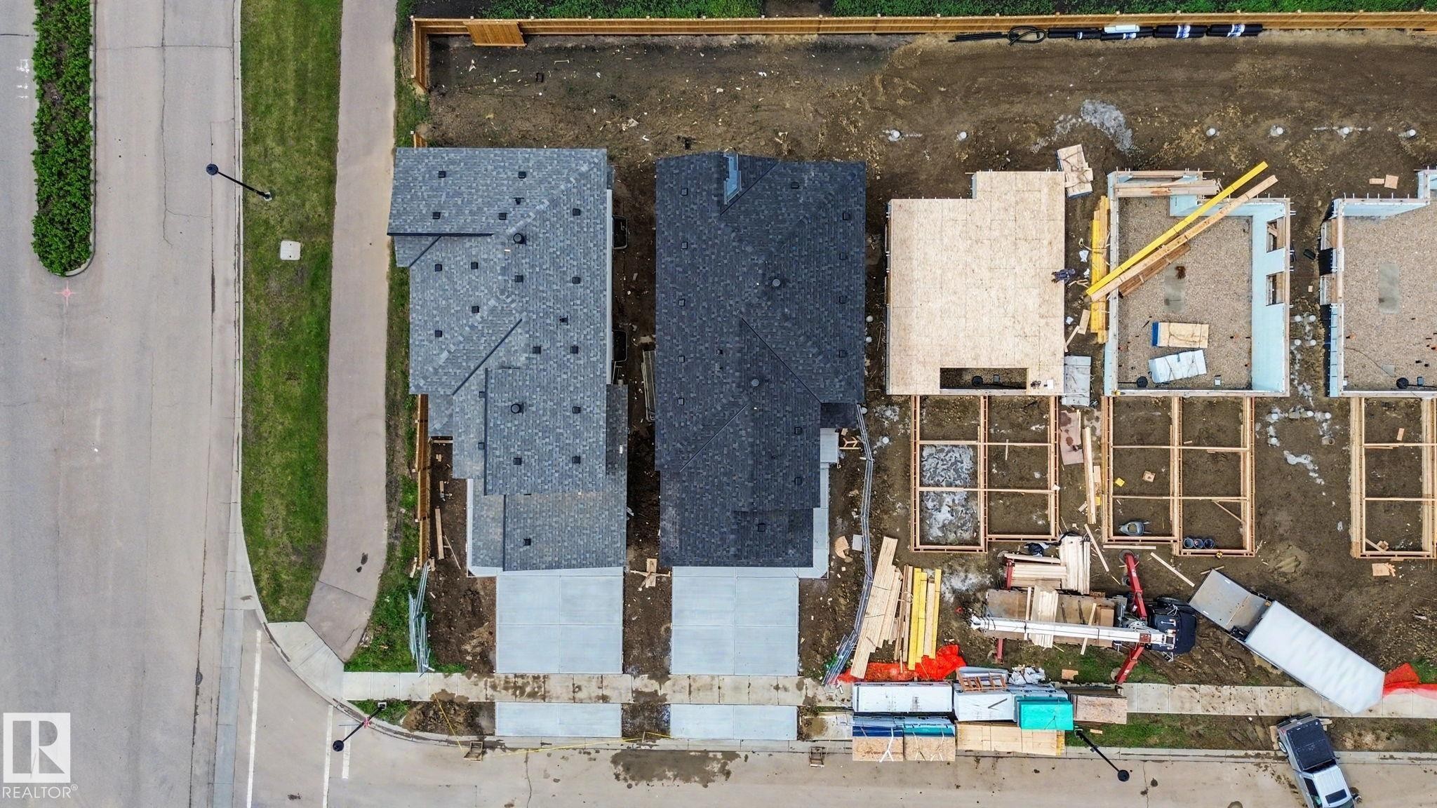 New construction site featuring multiple residential structures in various stages of development, from completed roofing to foundational framing - 4 Willow Heights Drive, Stony Plain, AB