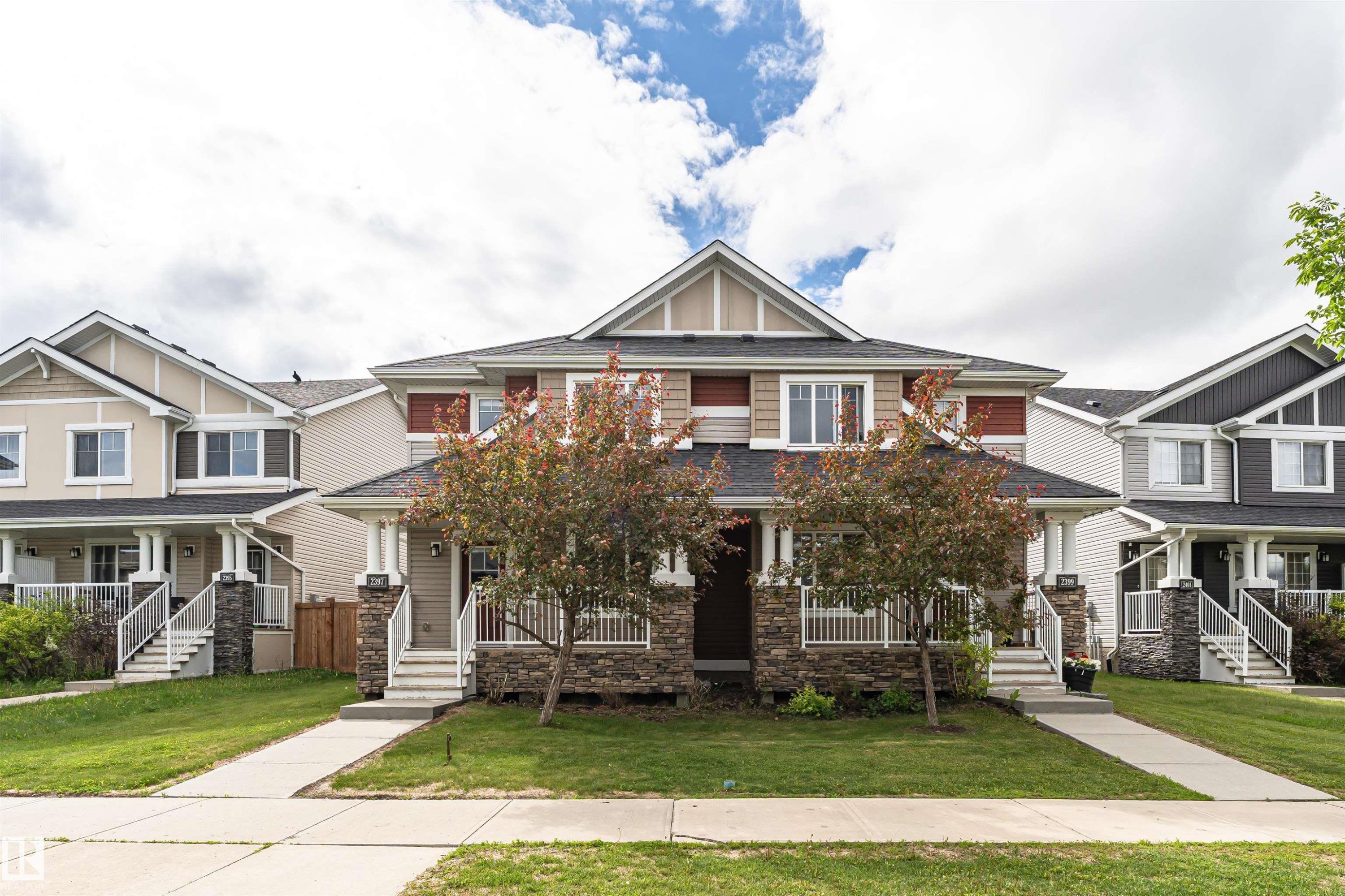 Contemporary duplex-style residence featuring stone veneer and siding facade, covered front entry porch, and a manicured lawn - 2397 Glenridding Boulevard, Edmonton, AB