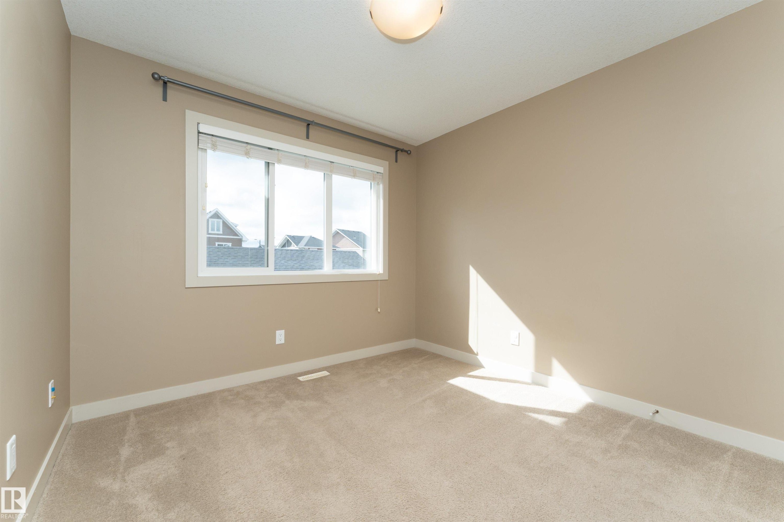 Room featuring light beige carpeting, neutral wall color, and a three-pane window with white trim - 2397 Glenridding Boulevard, Edmonton, AB