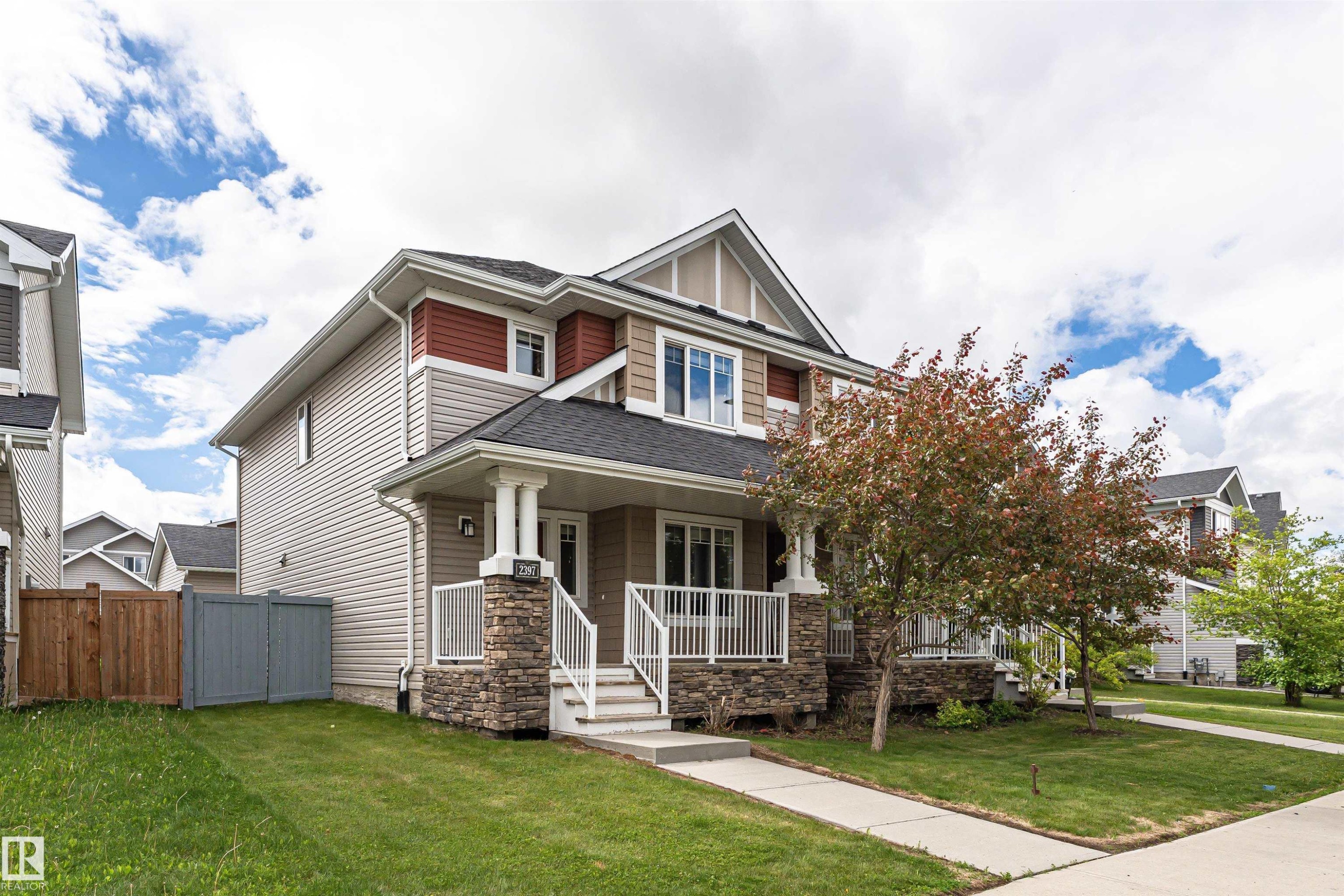 Multi-level exterior featuring stone veneer accents, light siding, and a covered front porch with white railings - 2397 Glenridding Boulevard, Edmonton, AB