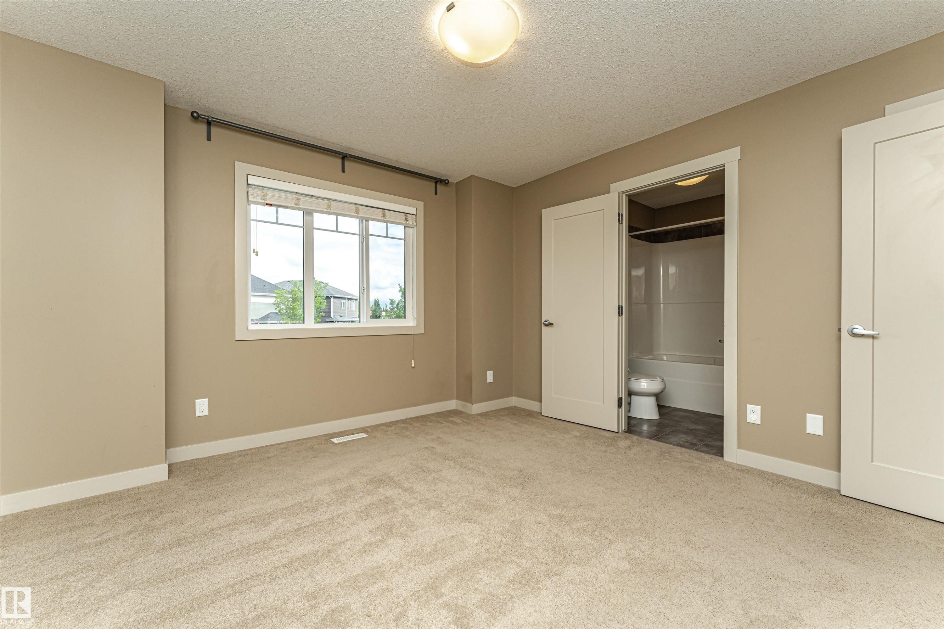 Carpeted room with a large window, a ceiling-mounted light fixture, and two panel doors - 2397 Glenridding Boulevard, Edmonton, AB