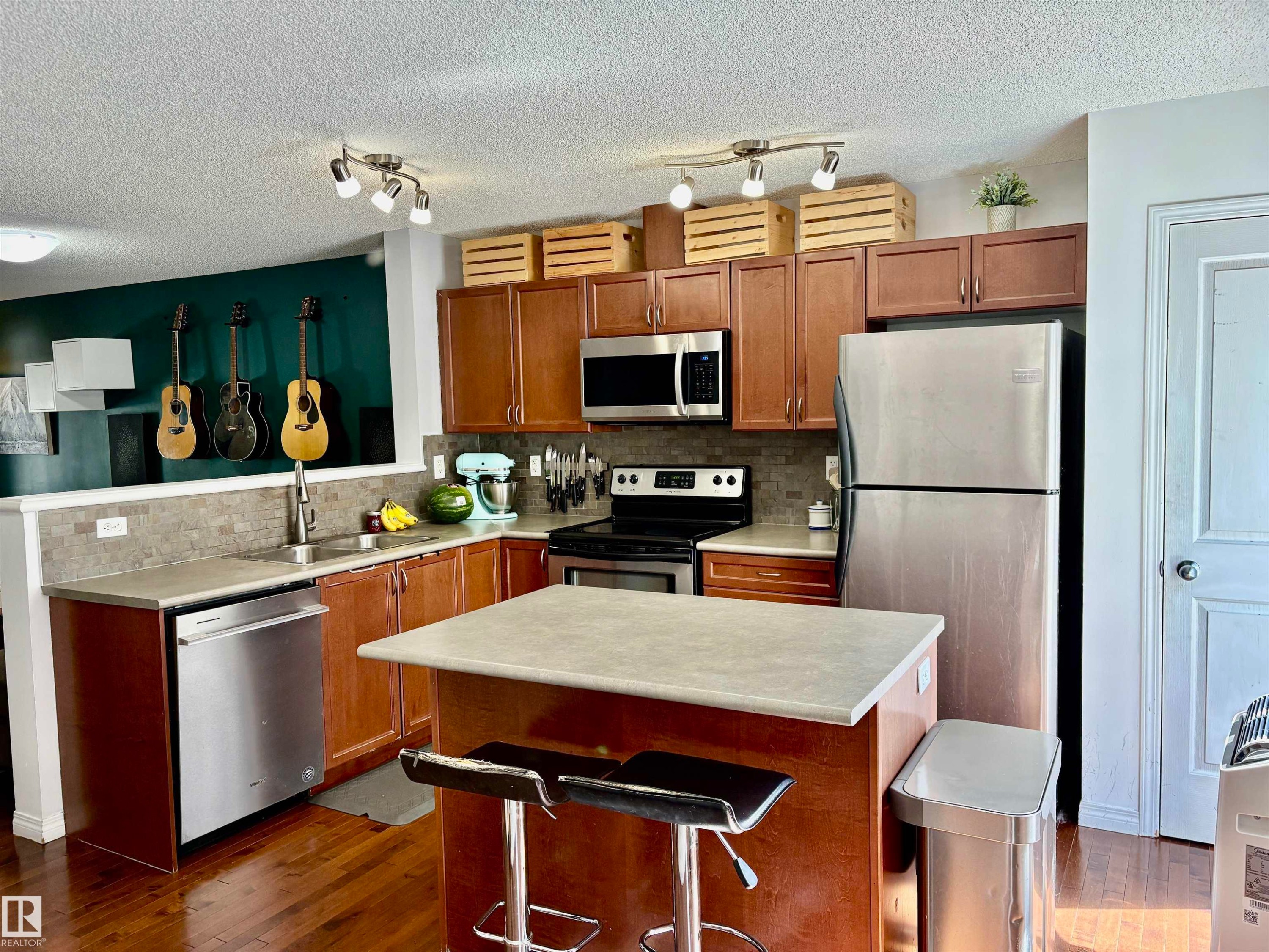 Kitchen featuring wood-finish cabinetry, stainless steel appliances, and a central island with a breakfast bar - 184 1804 70 Street, Edmonton, AB