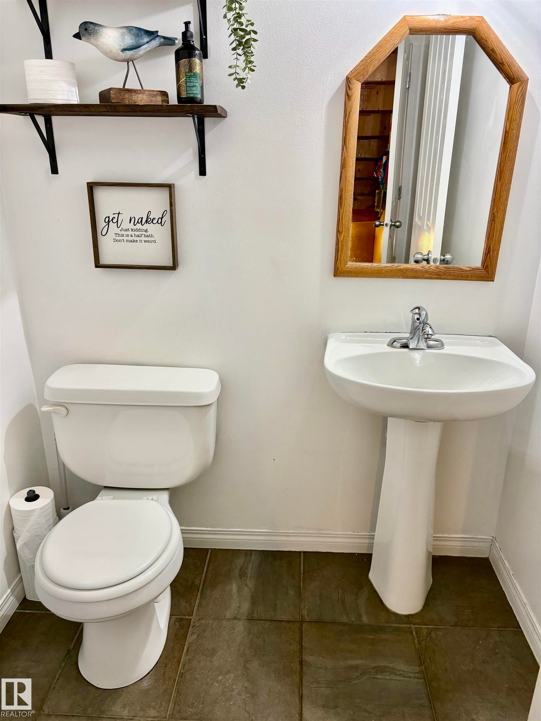 Well-appointed half bath featuring a white pedestal sink with a chrome faucet, a standard white toilet, and dark stone-look floor tiles - 184 1804 70 Street, Edmonton, AB