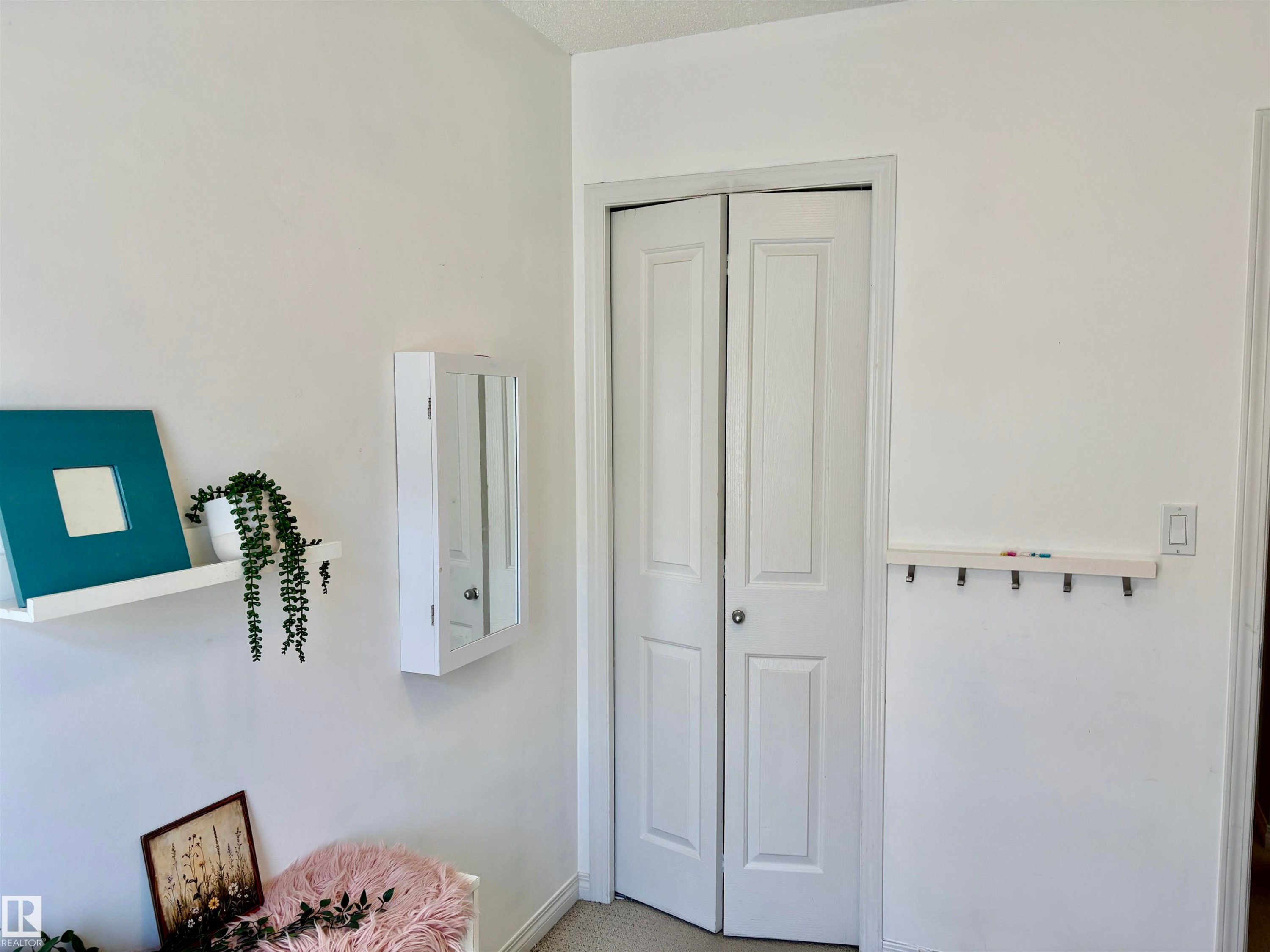 White bi-fold closet doors with round hardware, flanked by smooth white walls - 184 1804 70 Street, Edmonton, AB