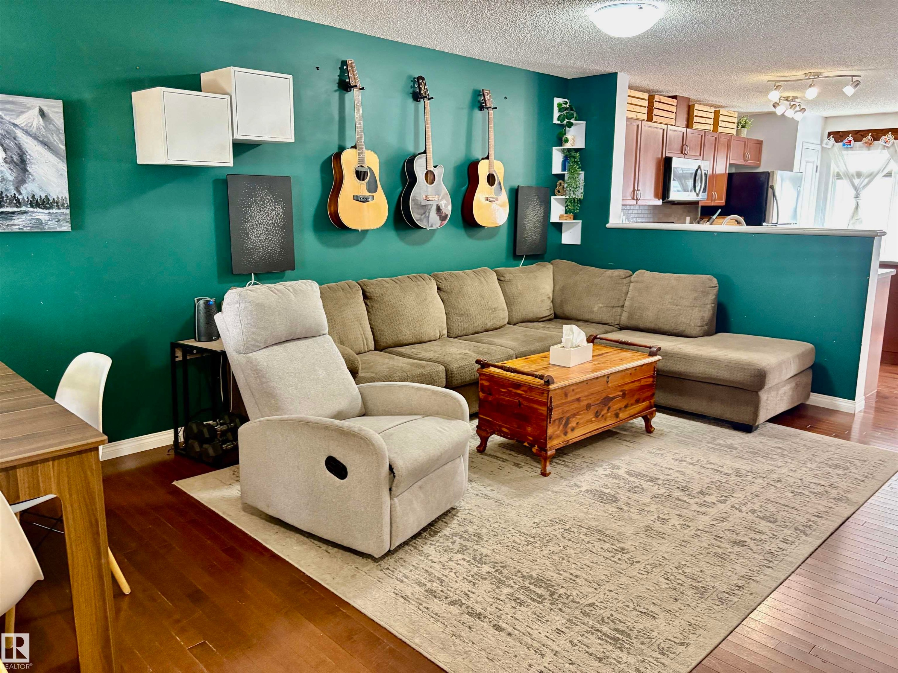 Open-concept living space featuring wood-finish flooring, a vibrant accent wall, and recessed lighting - 184 1804 70 Street, Edmonton, AB