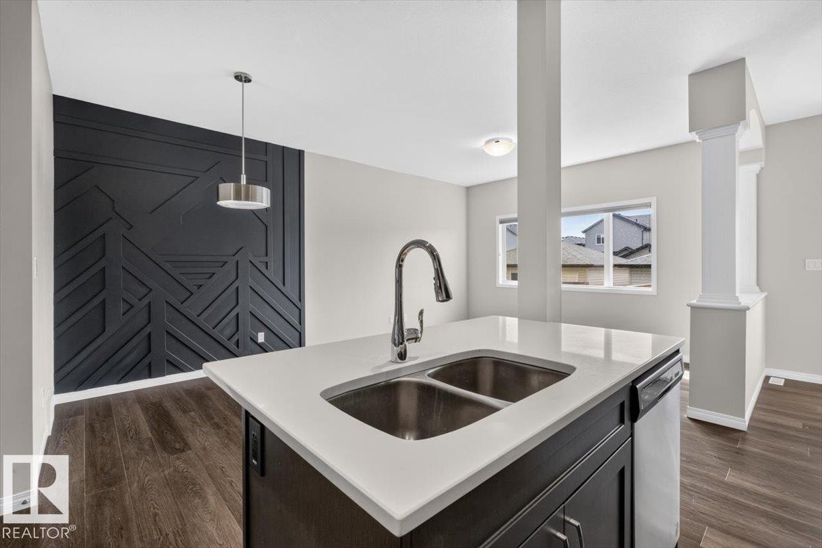 Kitchen island with a double stainless steel sink and gooseneck faucet - 2144 51 Street, Edmonton, AB