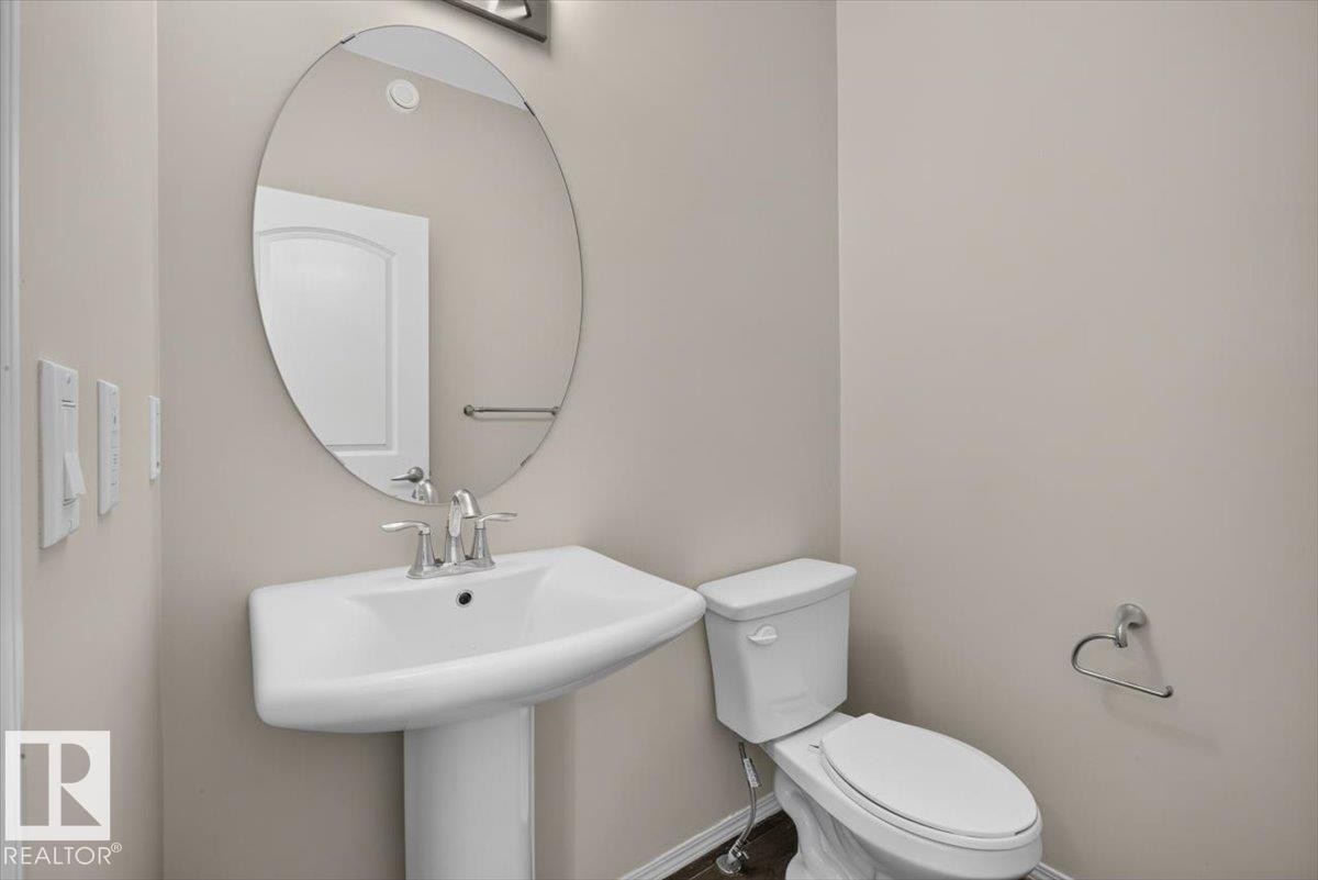 Pedestal sink with chrome faucet, complemented by an oval wall mirror and recessed lighting fixture - 2144 51 Street, Edmonton, AB