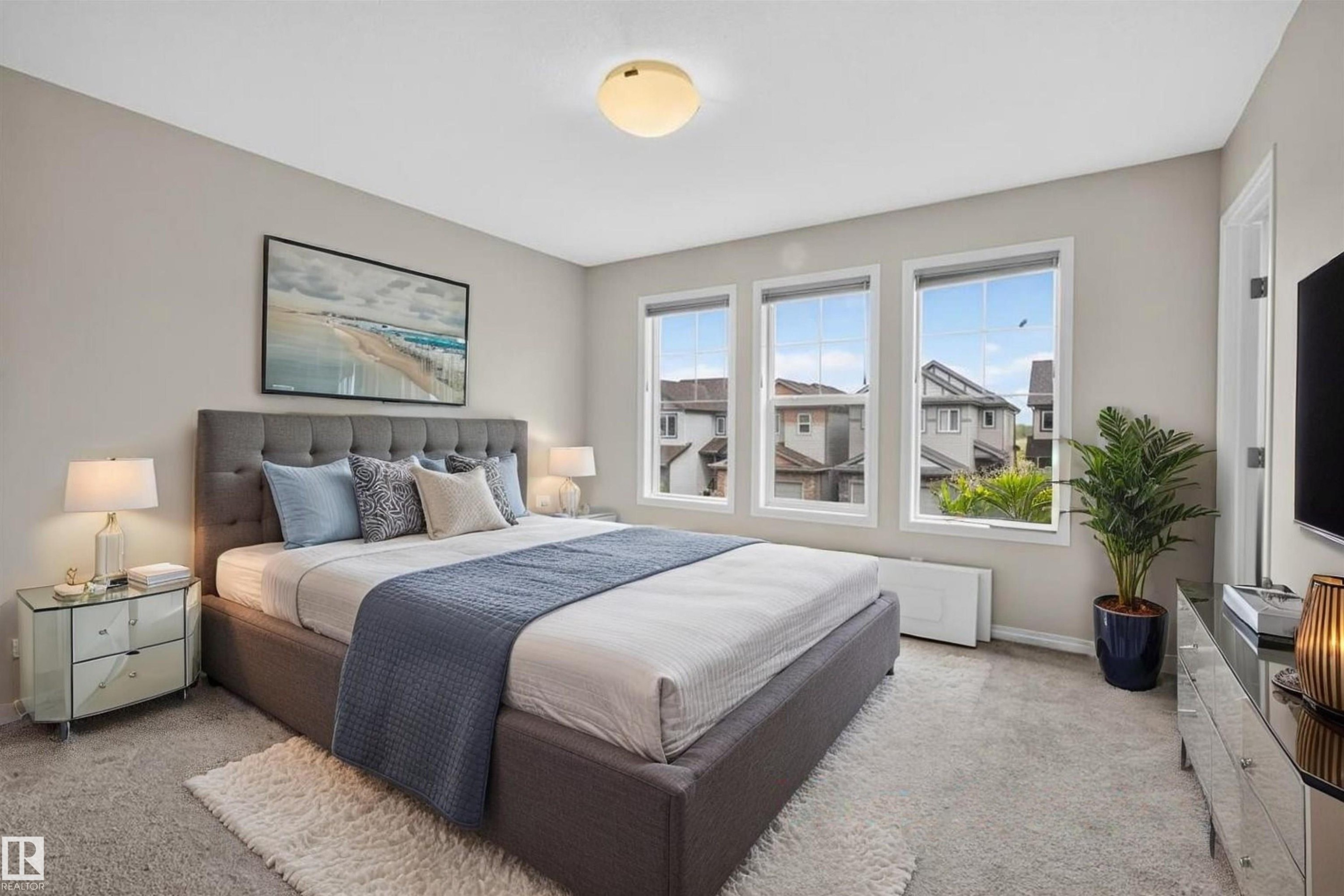 Spacious bedroom featuring multiple windows, neutral wall tones, and carpeted flooring - 2144 51 Street, Edmonton, AB