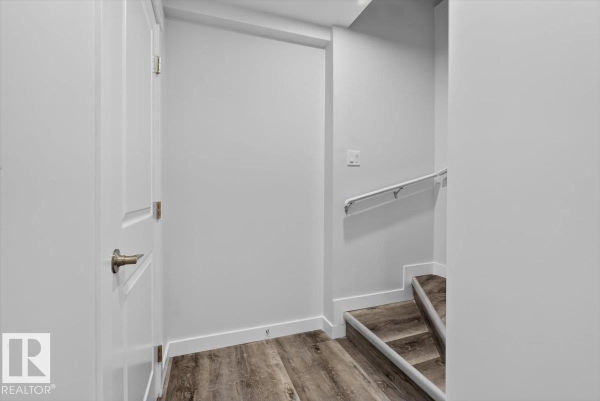Staircase with wood-finish treads and risers, featuring a white wall-mounted handrail - 2144 51 Street, Edmonton, AB