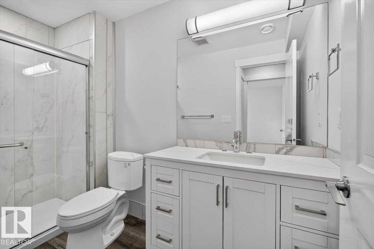 Bathroom featuring a white vanity with an integrated sink, polished chrome faucet, and rectangular mirror - 2144 51 Street, Edmonton, AB