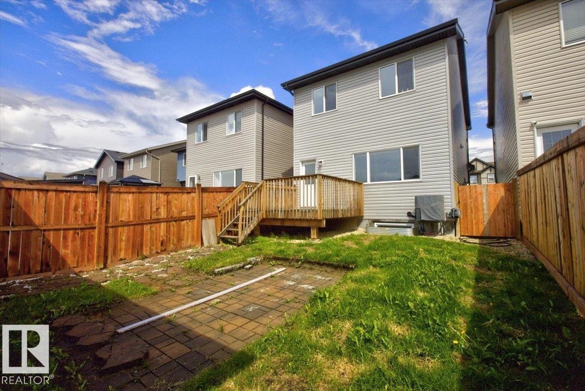 Fenced backyard featuring a wooden deck with stairs, a patio area, and a grass lawn - 2144 51 Street, Edmonton, AB