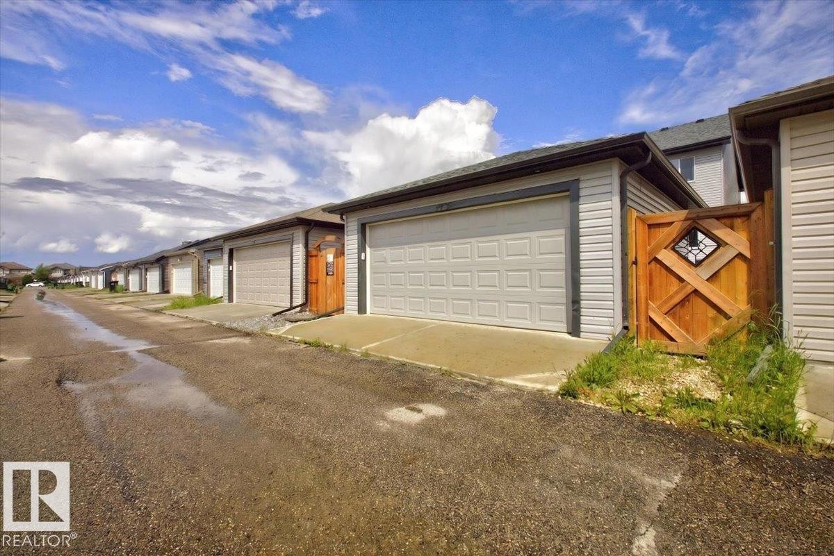 Detached garage featuring a paneled overhead door, light-colored siding, and a dark shingle roof - 2144 51 Street, Edmonton, AB