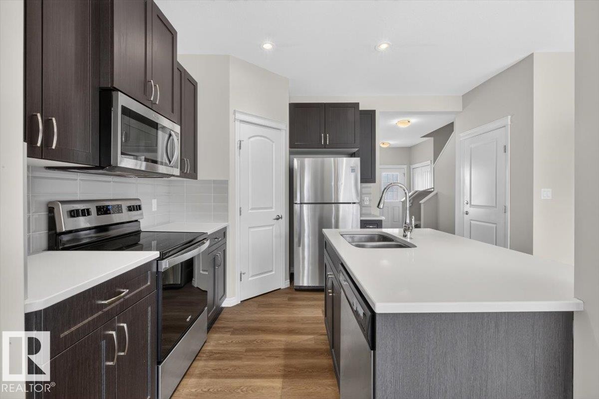 Modern kitchen featuring dark wood-finish cabinetry and stainless steel appliances - 2144 51 Street, Edmonton, AB