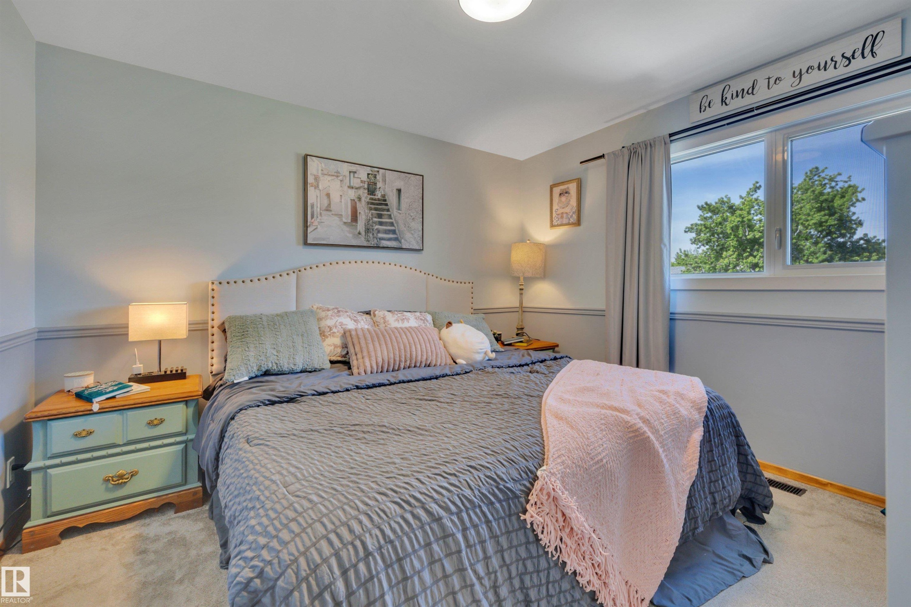 Carpeted bedroom with a window featuring natural light, a ceiling-mounted light fixture, and two-tone wall finishes - 9835 74 Street, Edmonton, AB