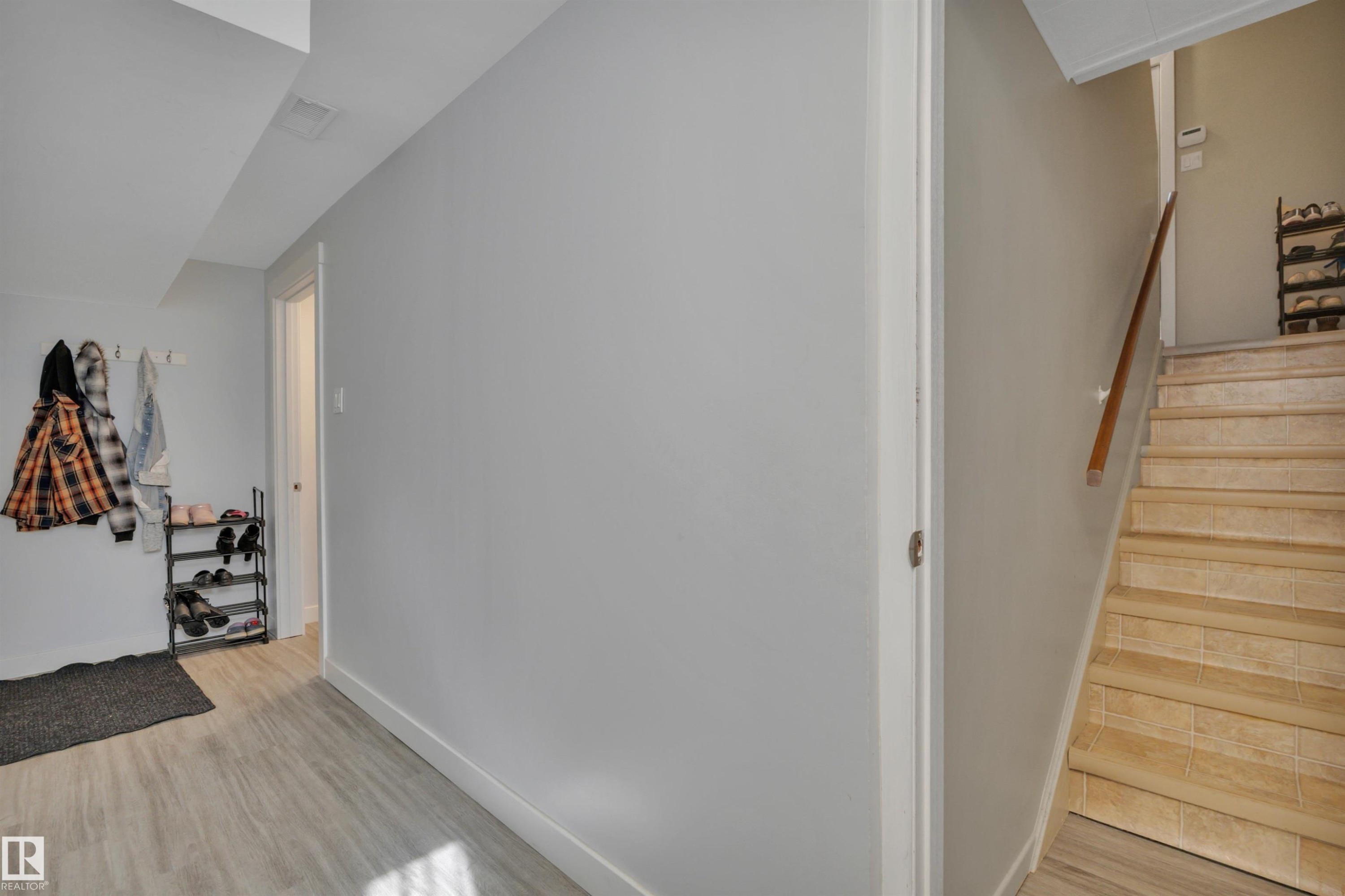 Staircase featuring light-toned tile treads and a wooden handrail - 9835 74 Street, Edmonton, AB