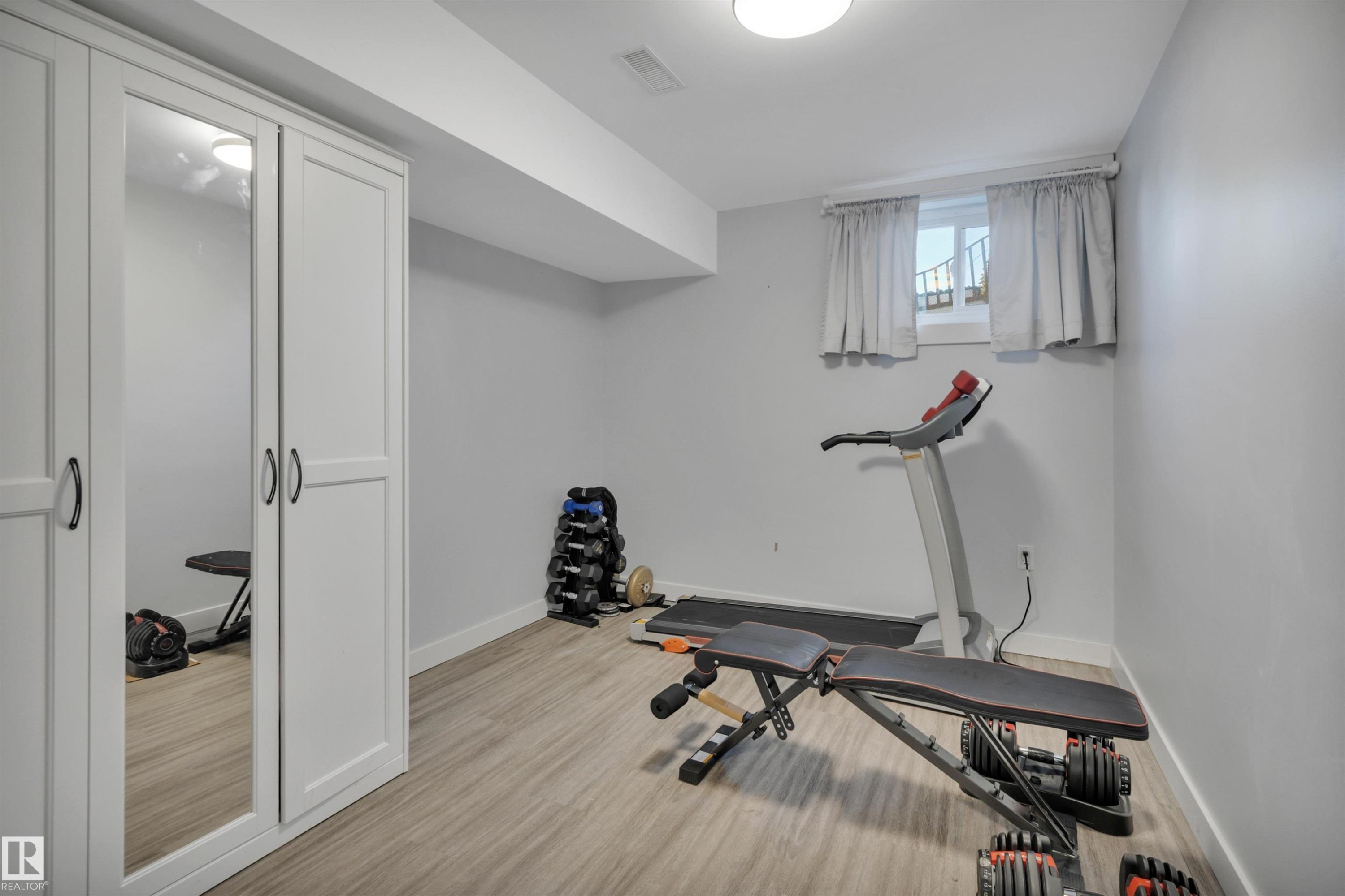 Finished room featuring light wood-finish flooring, white baseboards, and a neutral wall color - 9835 74 Street, Edmonton, AB